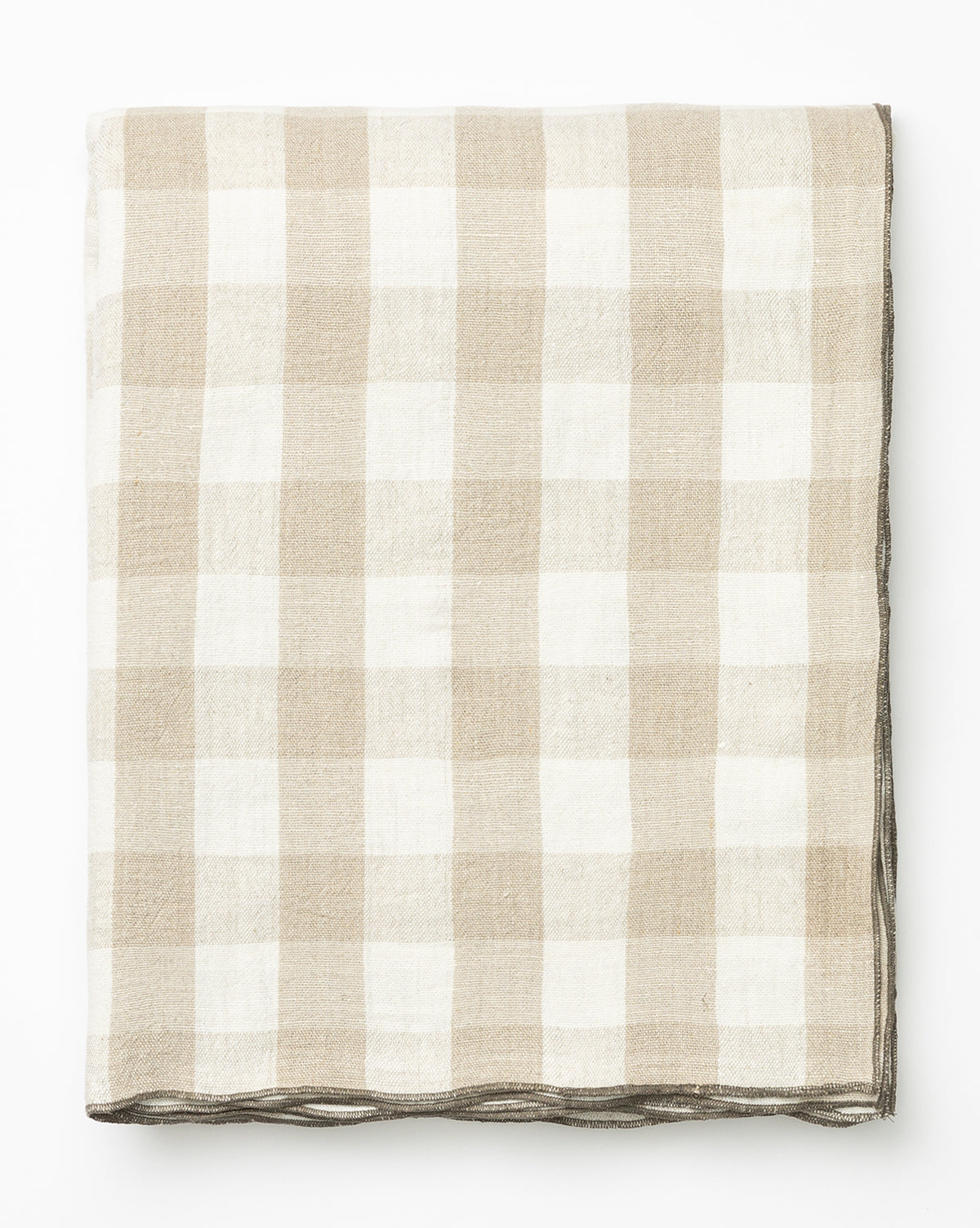 The Charlie Check Tablecloth, neatly folded, features a beige and white gingham pattern and is displayed on a white background by McGee & Co.