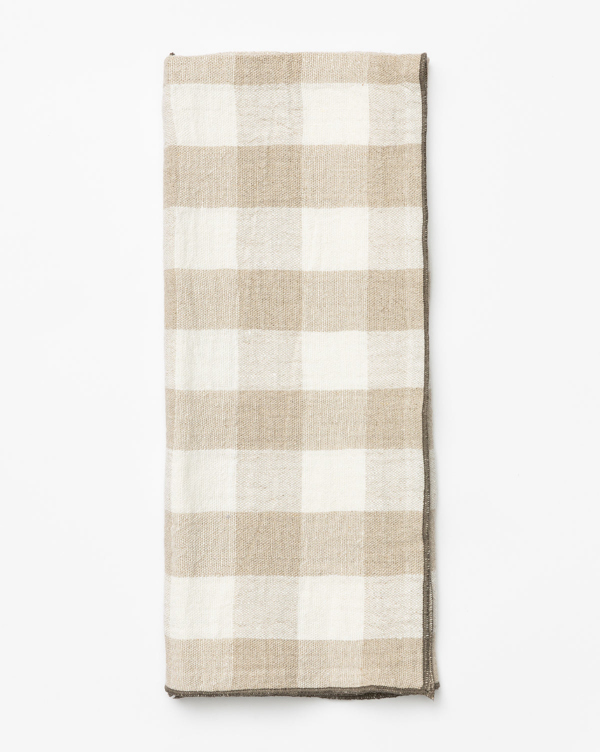 The Charlie Check Tea Towel, featuring a folded beige and white checkered linen pattern, is displayed on a white background—ideal for elegant table settings, by McGee & Co.