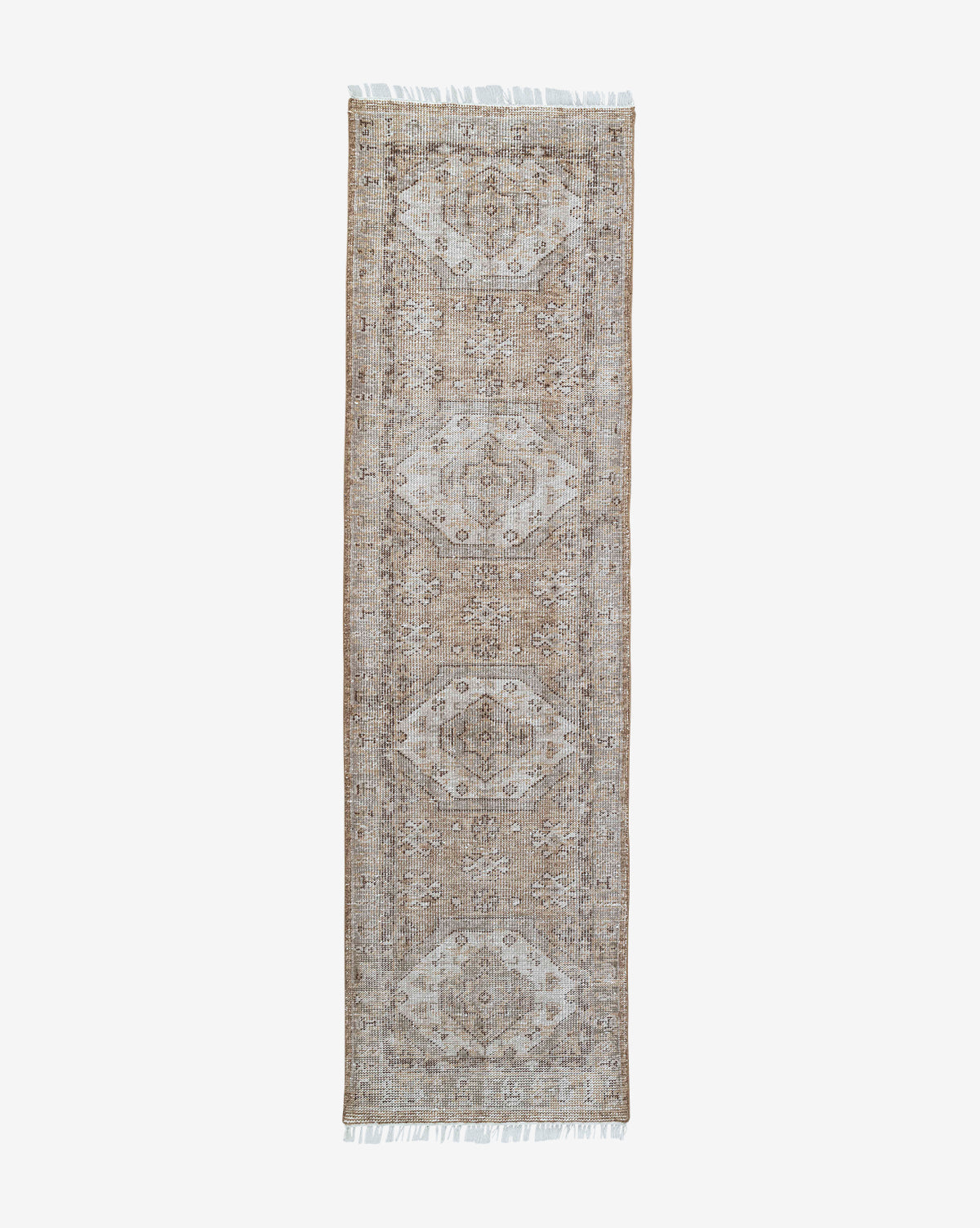 The Charlot Hand-Knotted Rug, rectangular in shape and shown on a white background, displays a beige and light brown geometric-floral pattern with short white fringes, by McGee & Co.