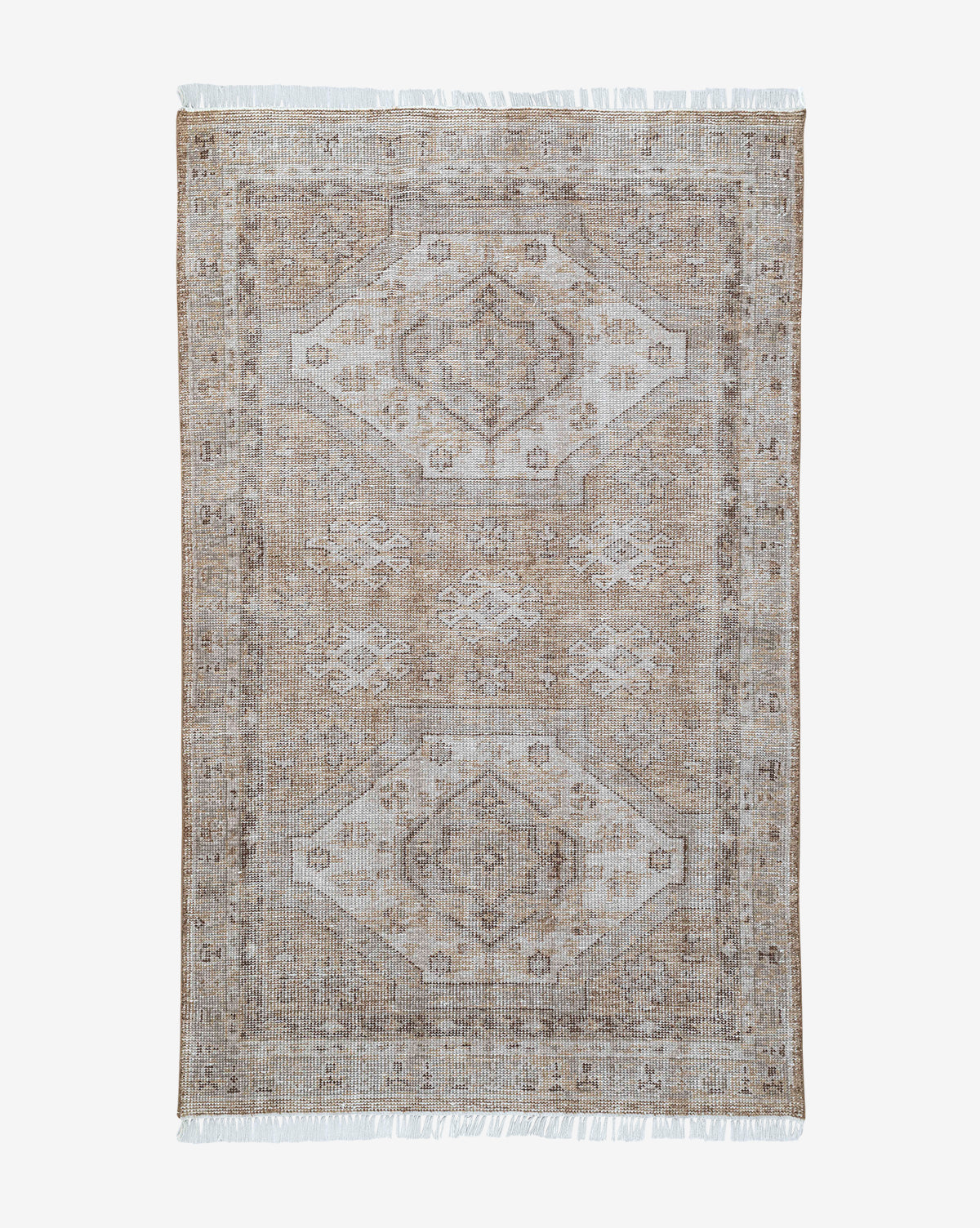 The Charlot Hand-Knotted Rug is a rectangular vintage piece in beige and light brown, featuring a faded geometric pattern with two central diamond shapes and fringed edges, by McGee & Co.