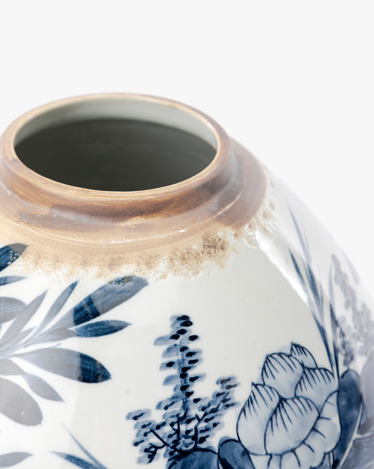 Close-up of the base of a Chinoiserie Ginger Jar with hand-painted blue and white floral patterns and brown discoloration near the rim, shown against a plain white background, by McGee & Co.