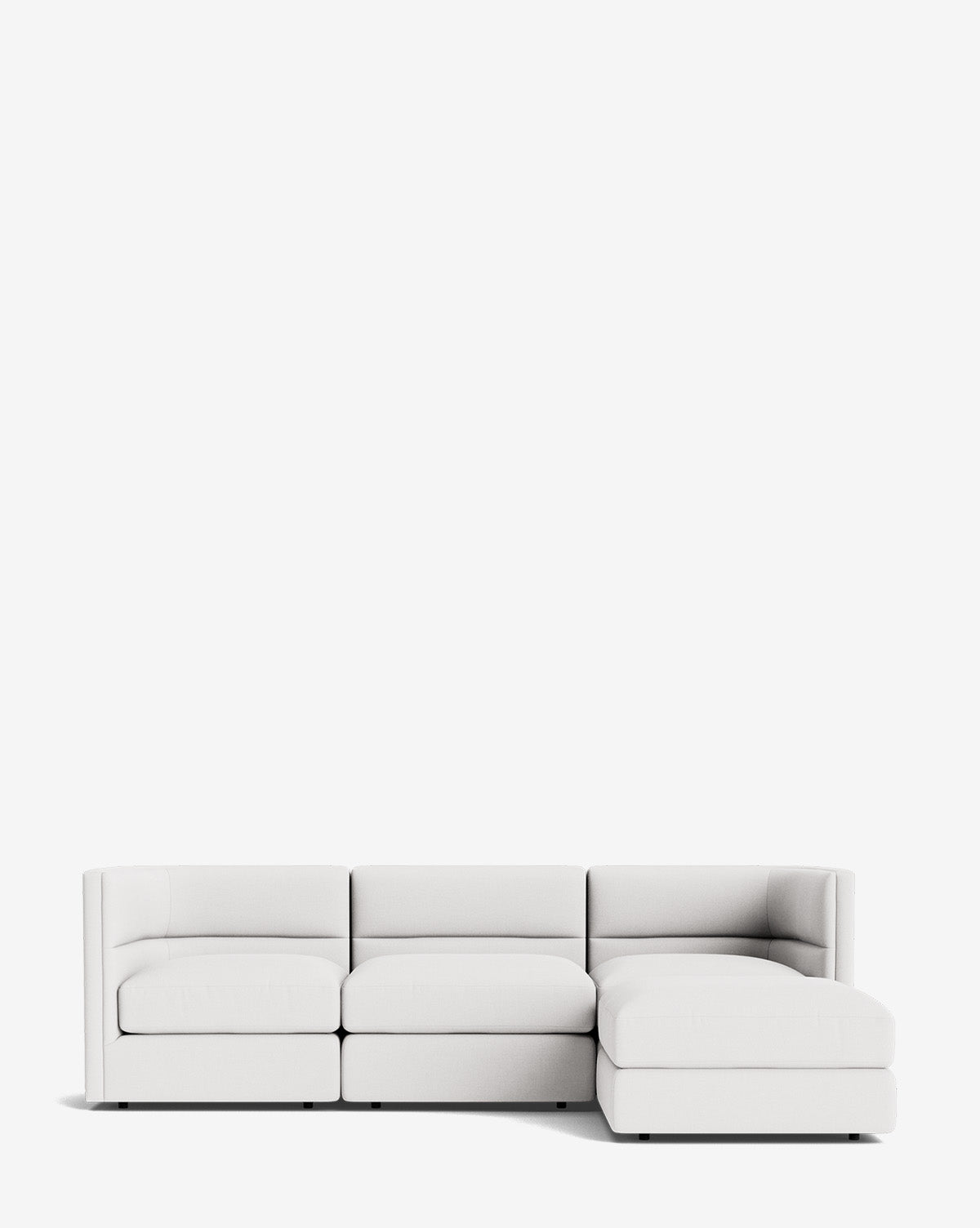 The Claremont Modular Sofa with Ottoman 99 is a modern white sofa featuring three seats, a right-side chaise lounge, and a sleek channeled back, set against a plain white background, by McGee & Co.