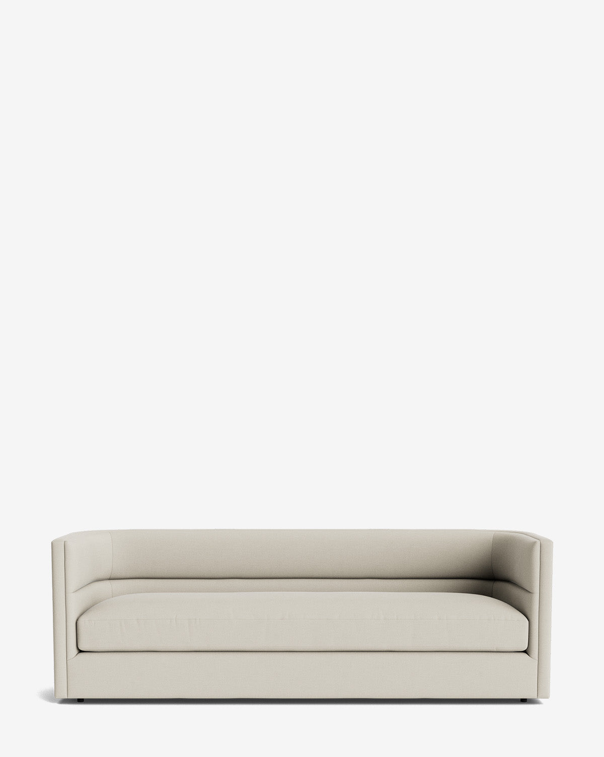 The Claremont Sofa 84 is a minimalist, modern light beige sofa with low, straight arms and back. Upholstered in high-quality fabric, it features a sleek design with no visible legs or decorative details, by McGee & Co.