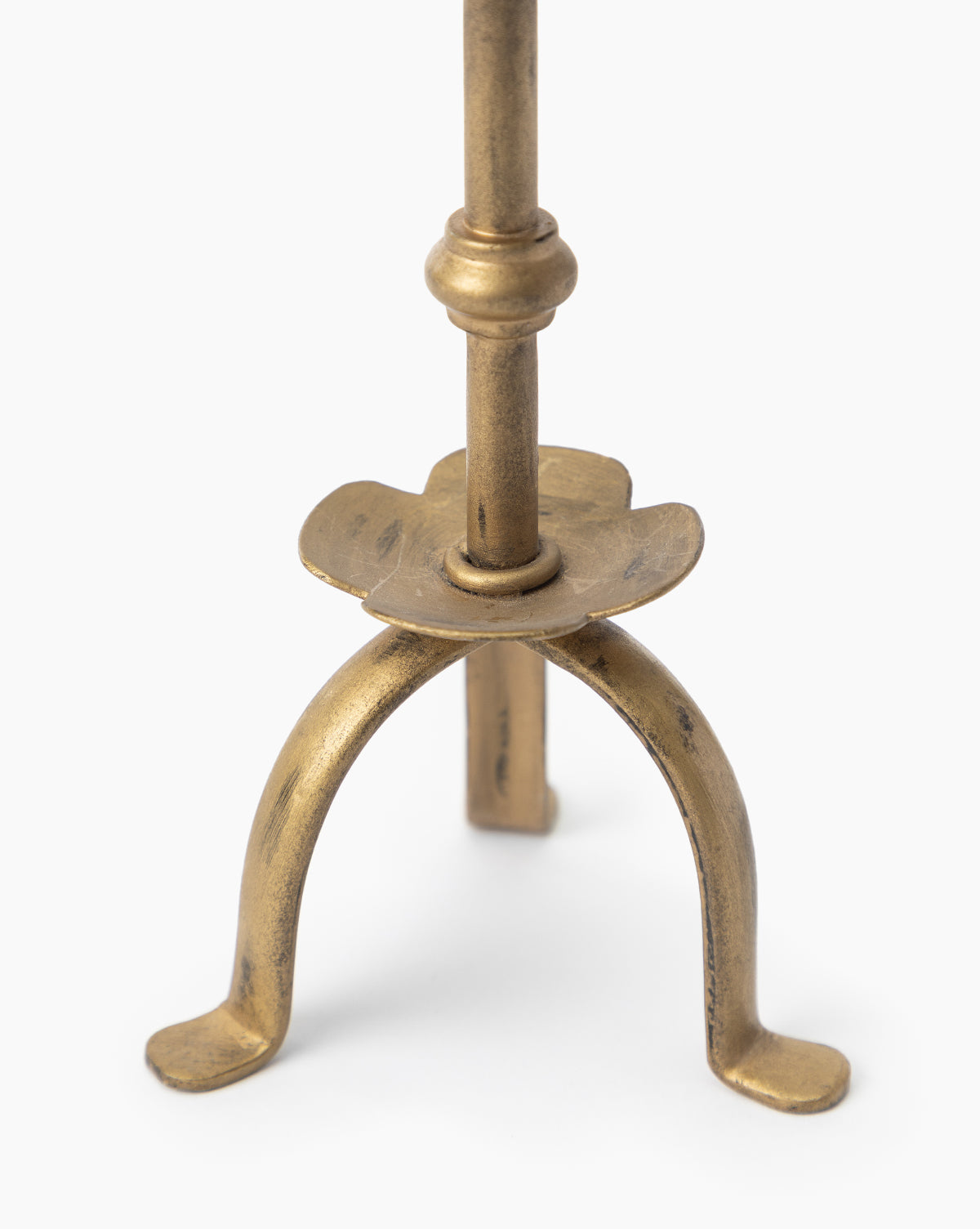 Close-up of the Claridge Taper Holder, showcasing its antique brass finish, vertical rod, circular detail, and three curved legs with rounded feet—an elegant accent for any mantel against a plain white background.