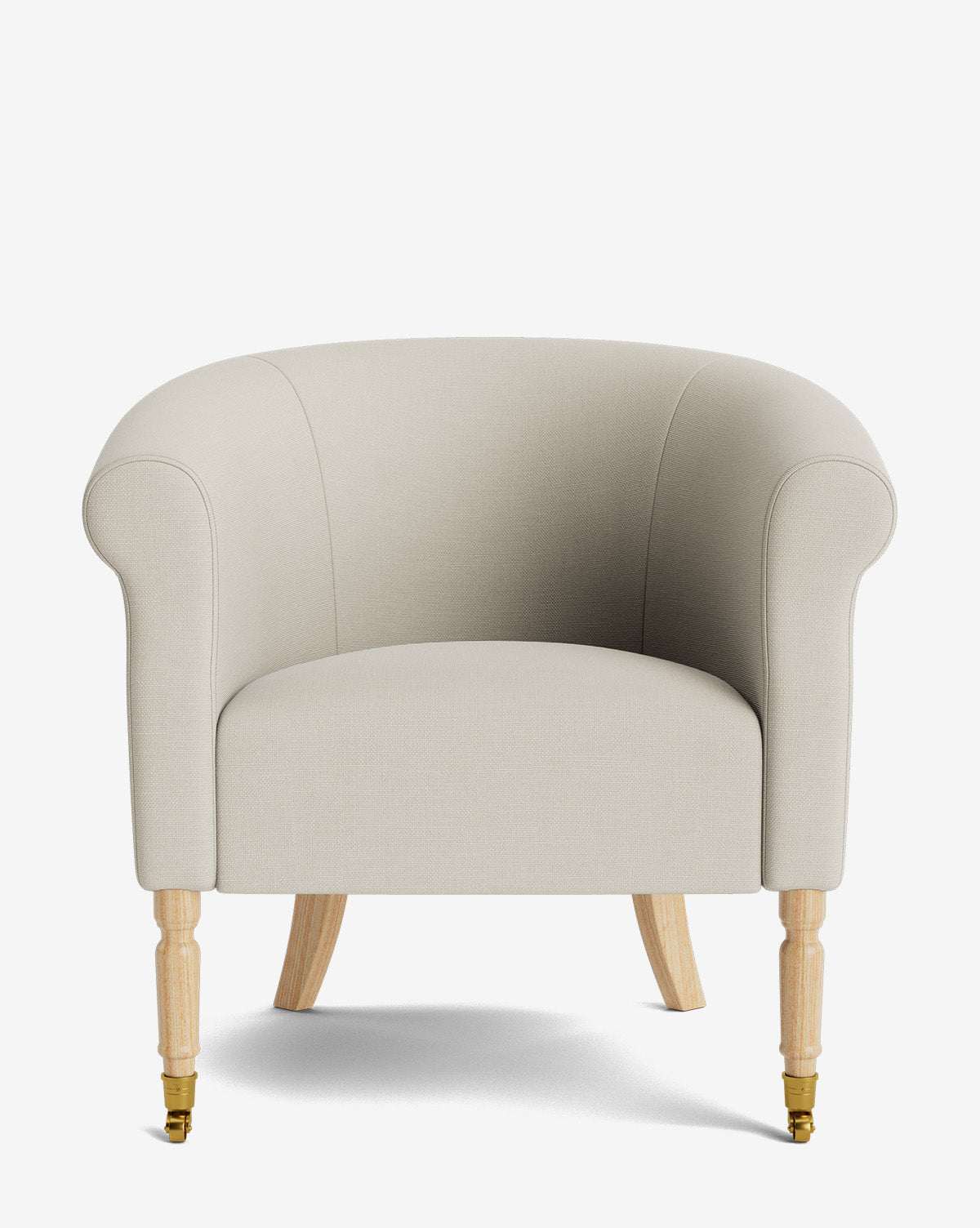 The Clemence Lounge Chair is a beige upholstered lounge chair with rounded arms and backrest, light wooden legs, and brass caster wheels on the front legs—an elegant classic piece ideal for timeless living rooms, by McGee & Co.