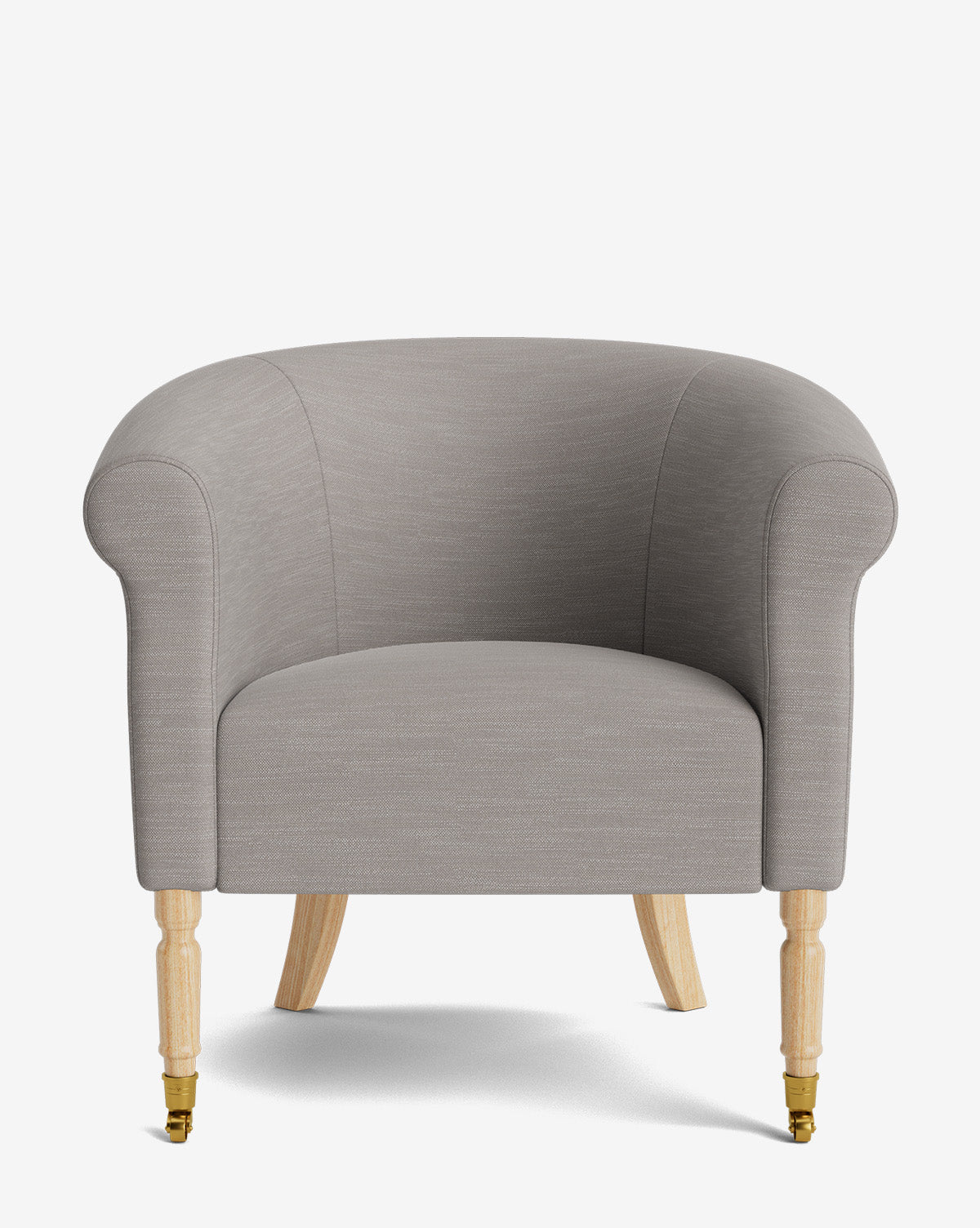 The Clemence Lounge Chair features light gray designer fabric upholstery, rounded arms and backrest, and four wooden legs—two with brass caster wheels—offering a modern, refined look perfect for any classic living room, by McGee & Co.