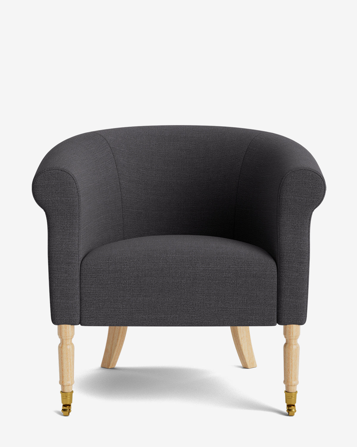 The Clemence Lounge Chair features a dark gray upholstered design with a rounded back and arms, designer fabric, light wood legs, and small brass casters on the front two legs, set against a plain white background by McGee & Co.