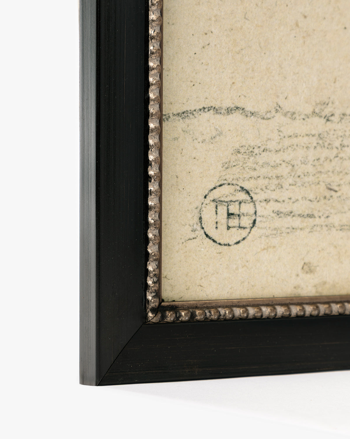 Close-up of a framed Clouded Island giclée on paper, showing its black frame with textured inner border and part of a faded circular stamp on the aged artwork, by McGee & Co.