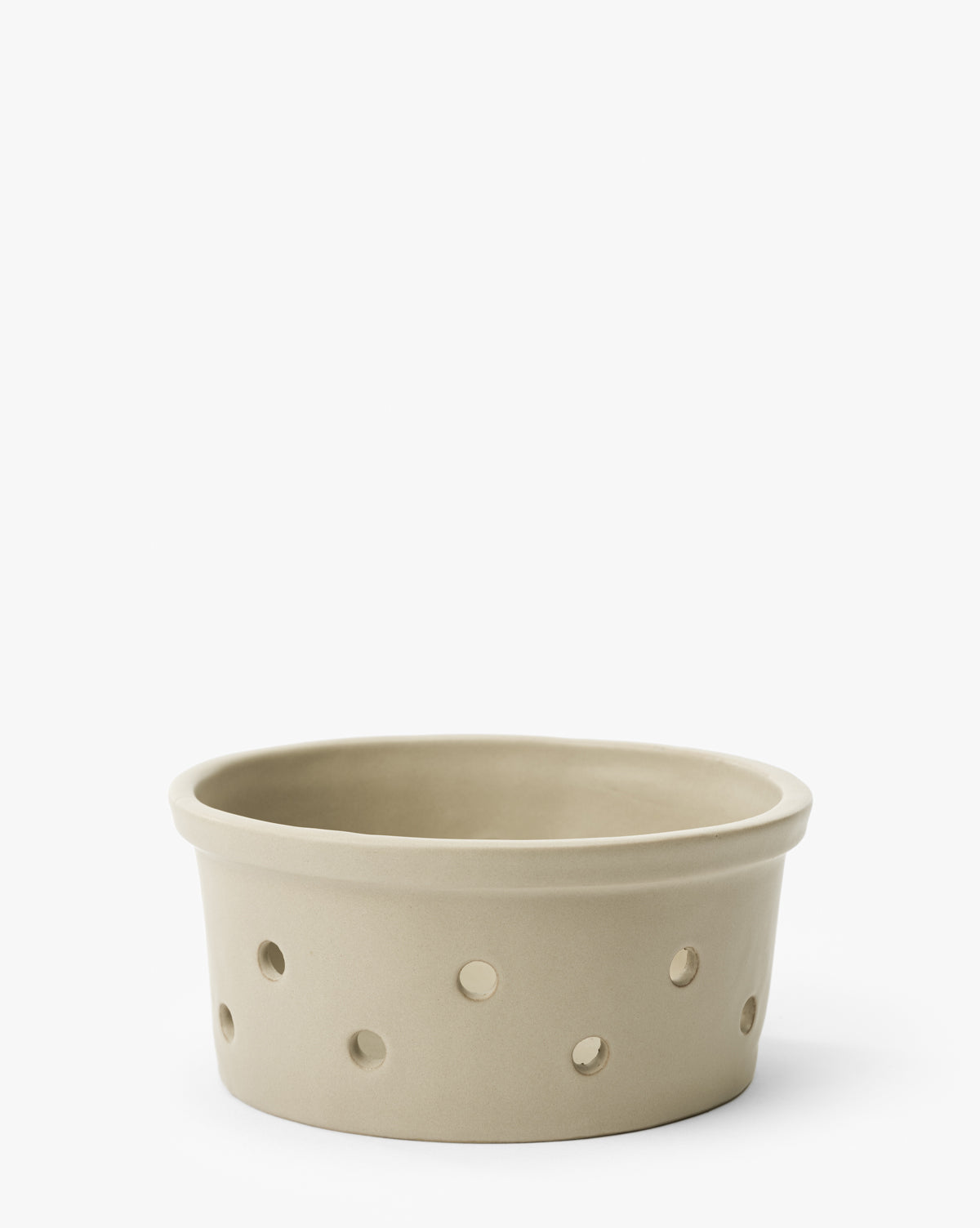 The Coen Berry Bowl is a round, beige stoneware bowl with a matte finish and several evenly spaced circular holes around its sides, shown against a plain white background by McGee & Co.