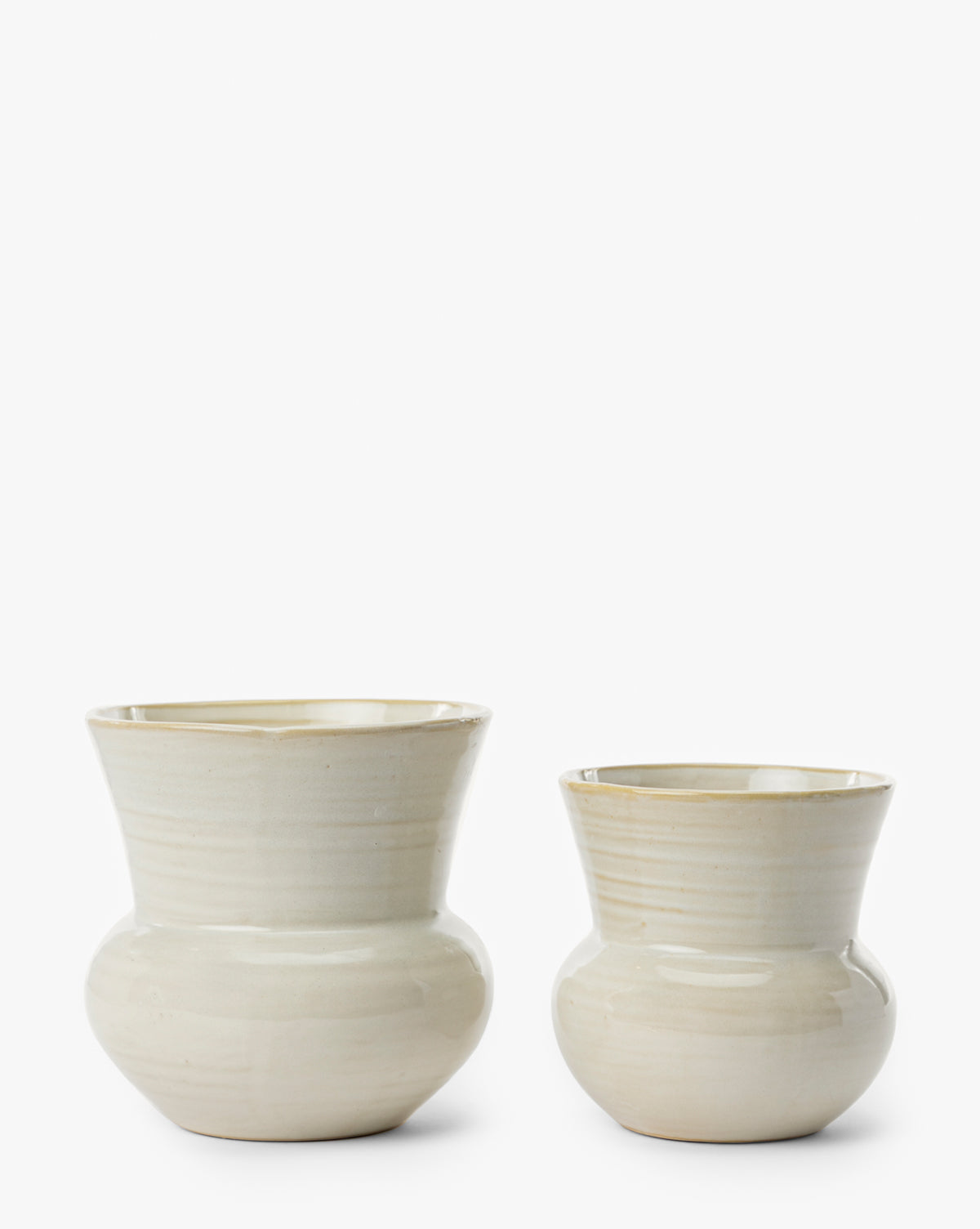 Two cream-colored Colchester Planters by Napa Home & Garden with a glossy finish, rounded base, and tapered rim are displayed side by side against a plain white background. Ideal as home decor or as ceramic planters. McGee & Co.