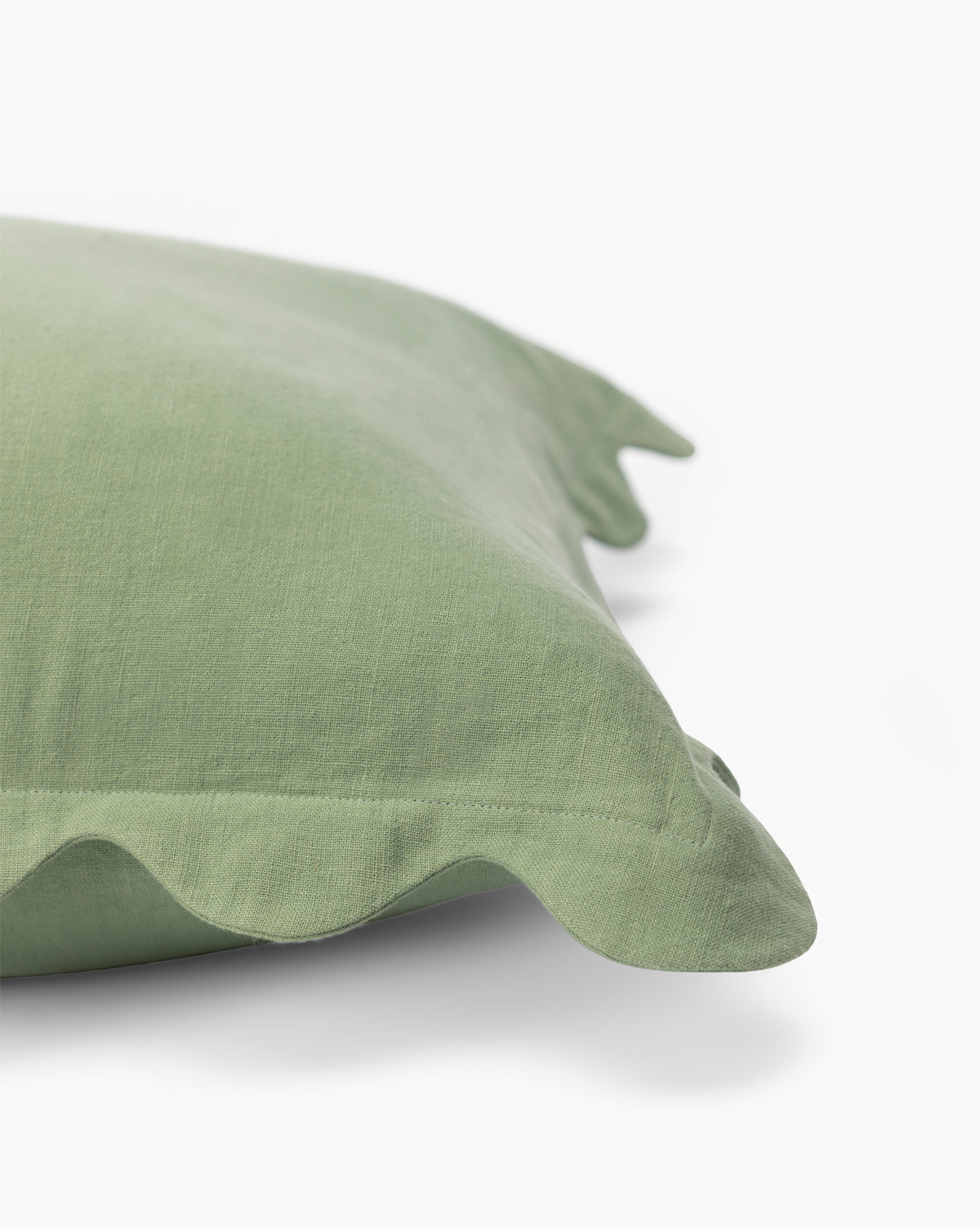 A close-up of the McGee & Co. x Loeffler Randall Colette Scallop Border Pillow Cover in pale green linen with a ruffled edge, shown on a white background—perfect for bringing chic style to your space, by McGee & Co.