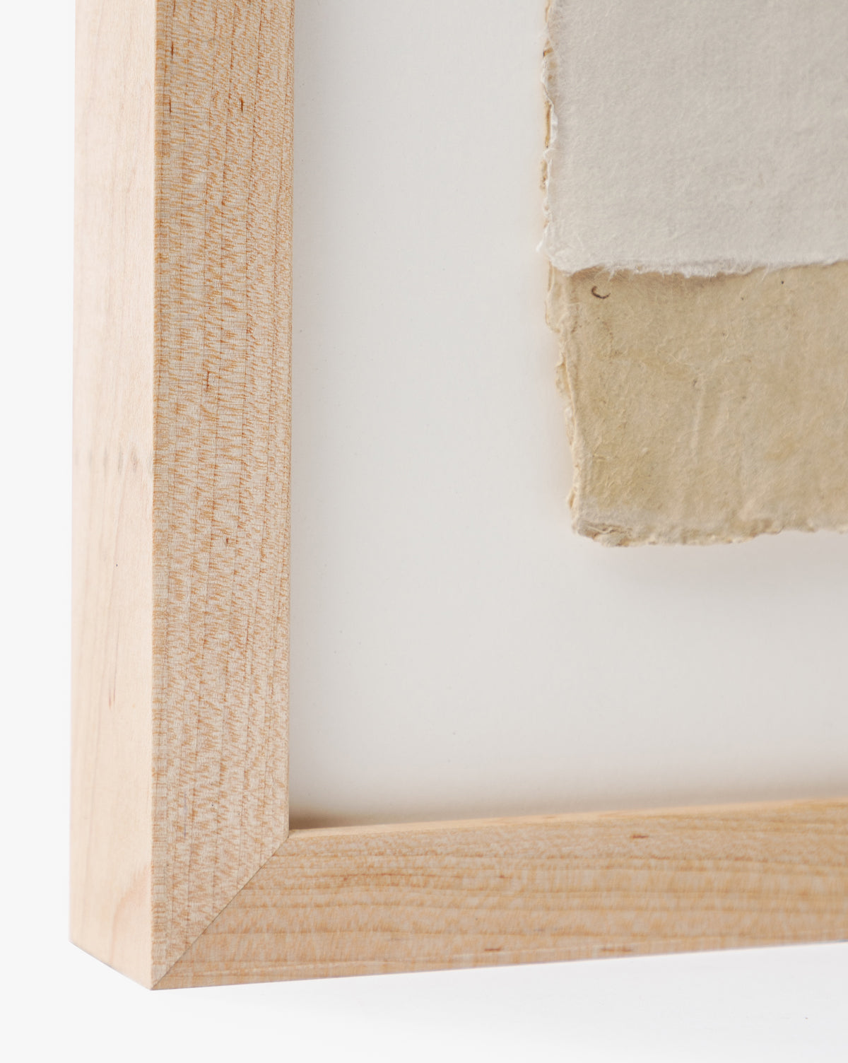 Close-up of a maple wood frame corner with two overlapping handmade papers—off-white and beige—mounted inside. This is Collage 2, ideal for neutral wall decor, shown against a white background.