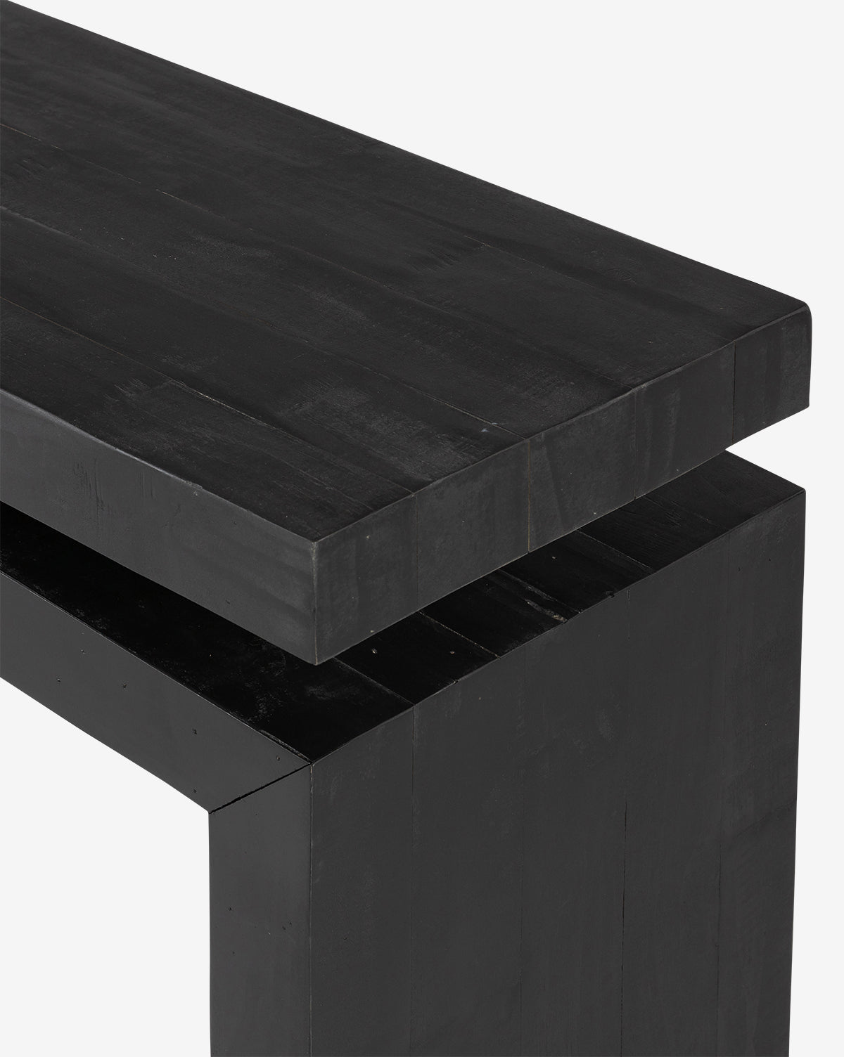 A close-up of the Colter Console Table—a modern black wooden piece with clean lines, crafted from reclaimed wood—showing its edge and corner against a white background, by McGee & Co.