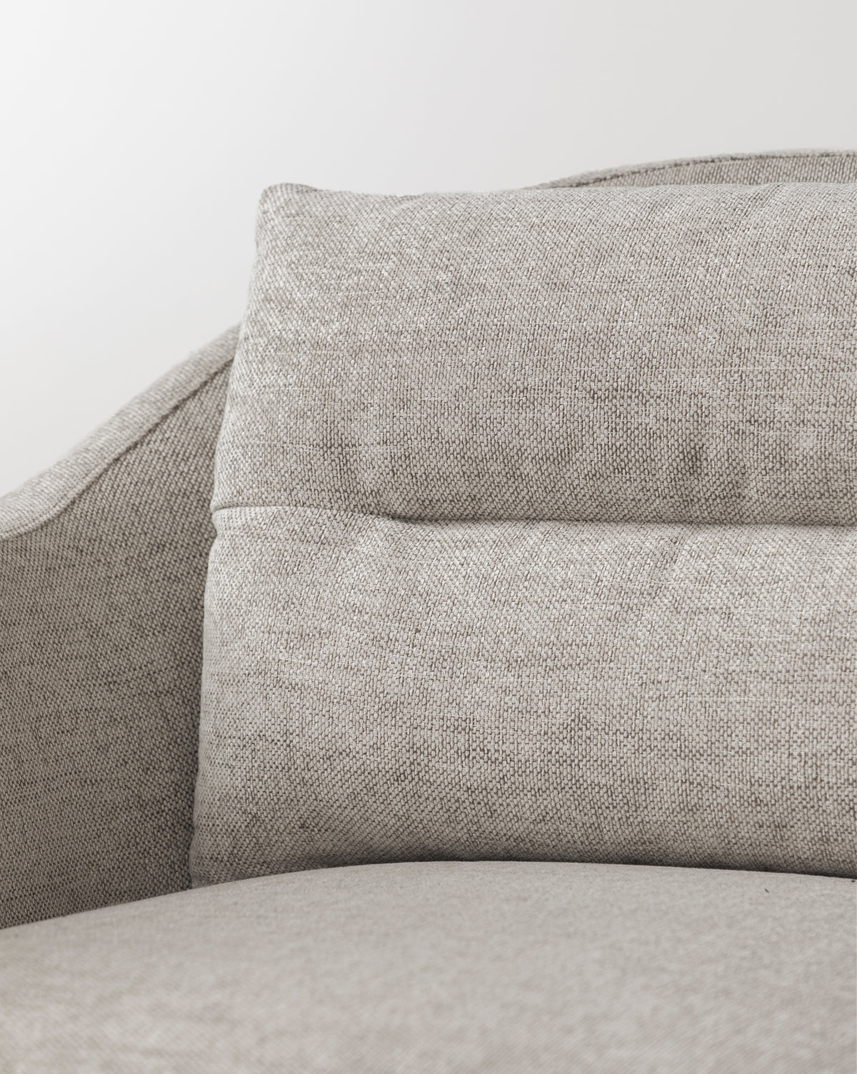 Close-up of the Commodore Lounge Chair in light gray, textured twine Crypton fabric, featuring a cushioned backrest and curved armrests, shown against a plain white background, by McGee & Co.