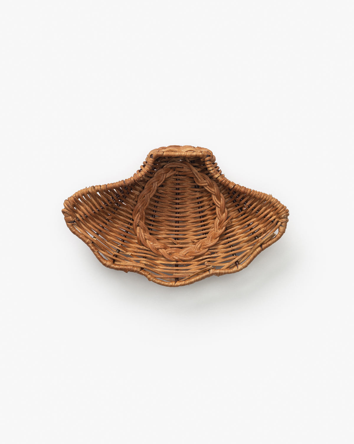 The Concha Dish is a handwoven caramel rattan basket shaped like a scallop shell, with a small top handle and curved textured design, displayed against a plain white background by McGee & Co.