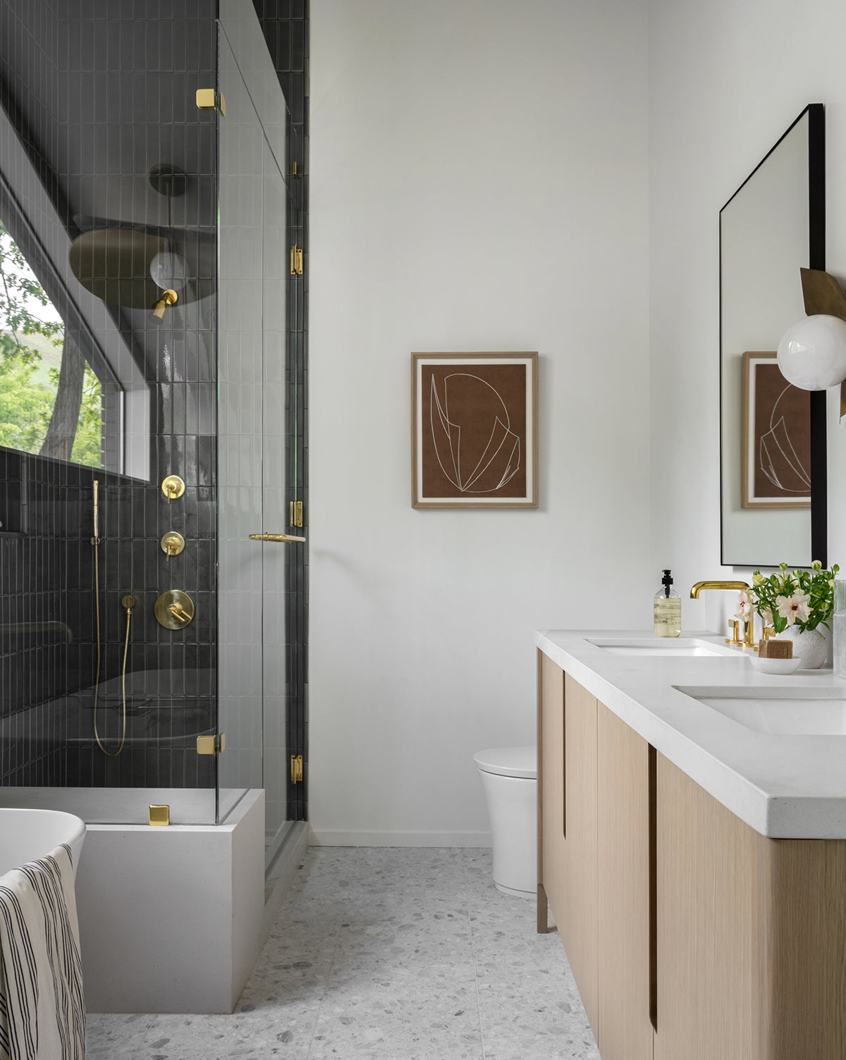 Modern bathroom with a glass shower and gold fixtures, double sink vanity with light wood cabinets, large mirror, and minimalist decor in neutral tones featuring the Contour Study I organic wall art in a natural wood frame.
