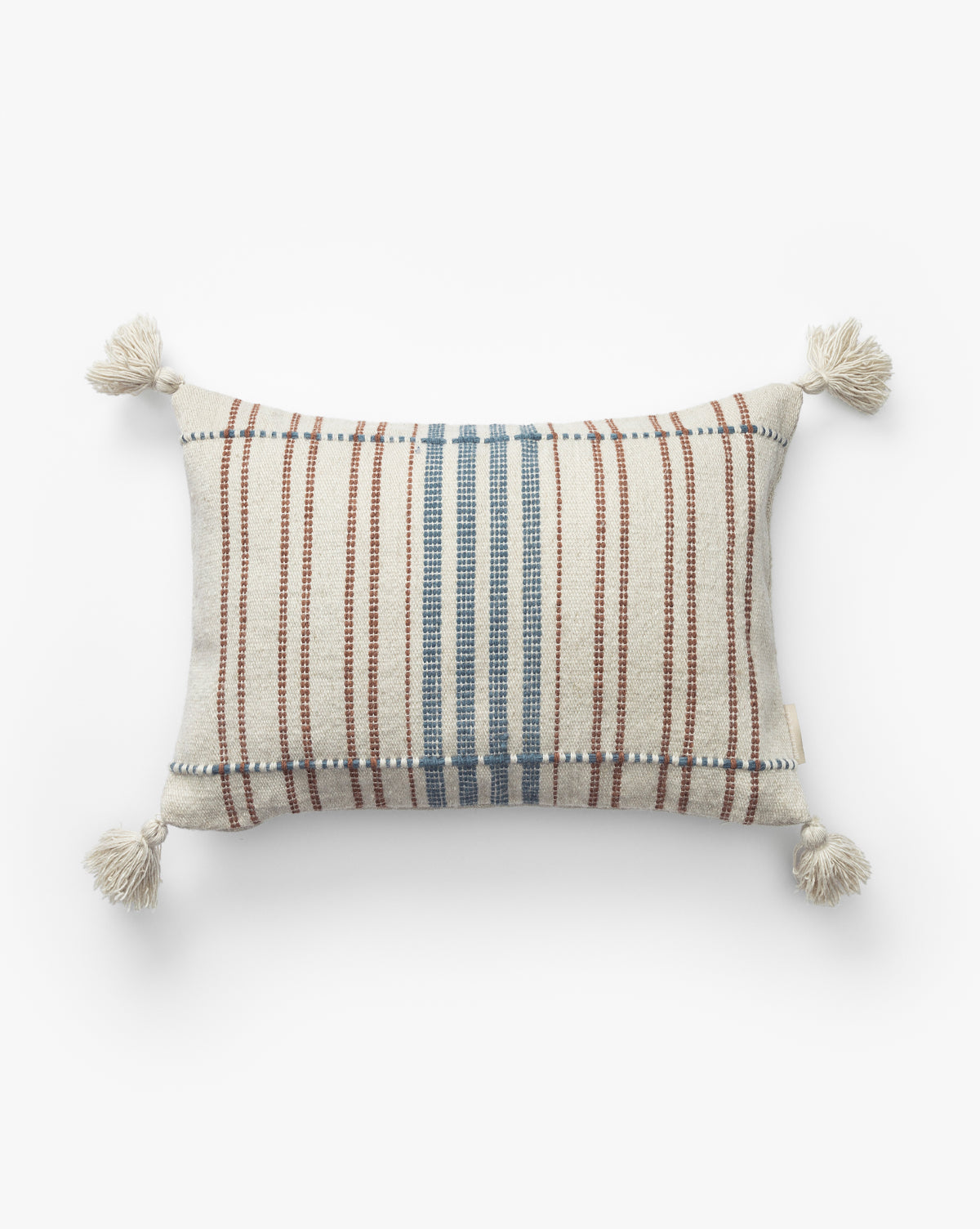 The Conrad Indoor/Outdoor Pillow features cream-colored fabric with blue and brown vertical stripes and cream tassels on each corner, by McGee & Co. Shown against a plain white background, this rectangular striped pillow adds decorative flair.
