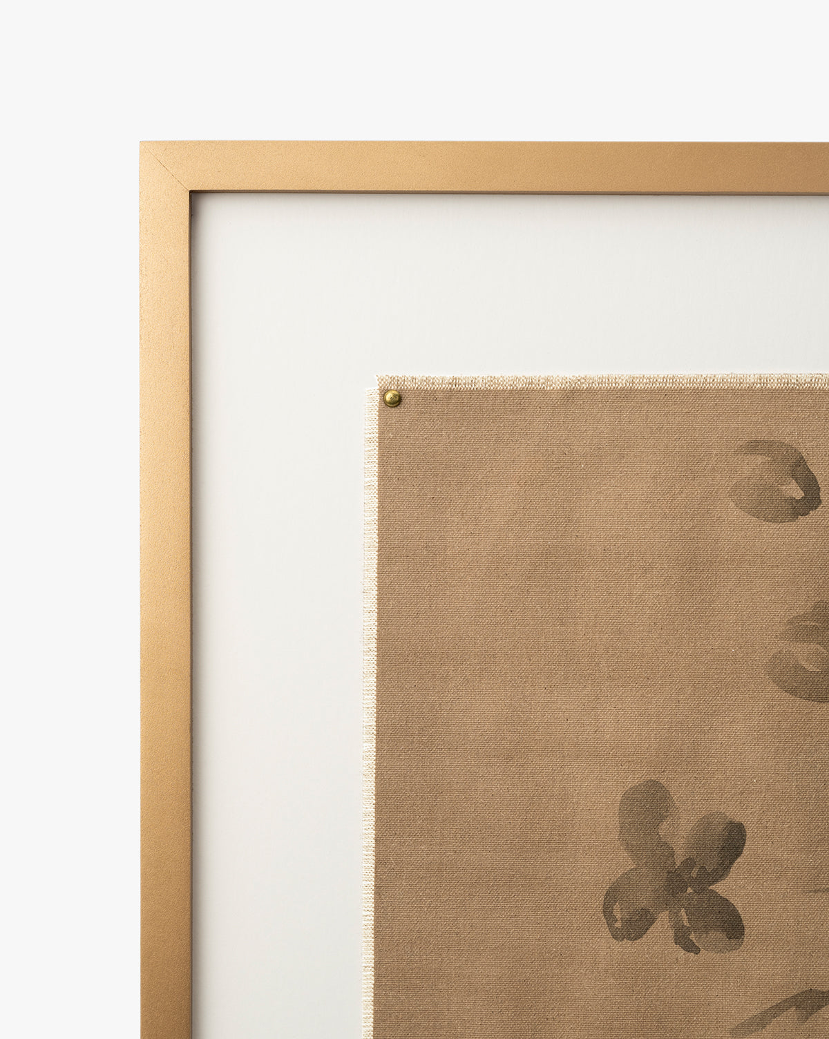 A close-up of a gold frame showcasing Consider the Wildflowers by Katie Mulder, a giclee print with abstract dark brushstrokes on beige canvas, secured at the corner with a brass nail against a white background, by McGee & Co.