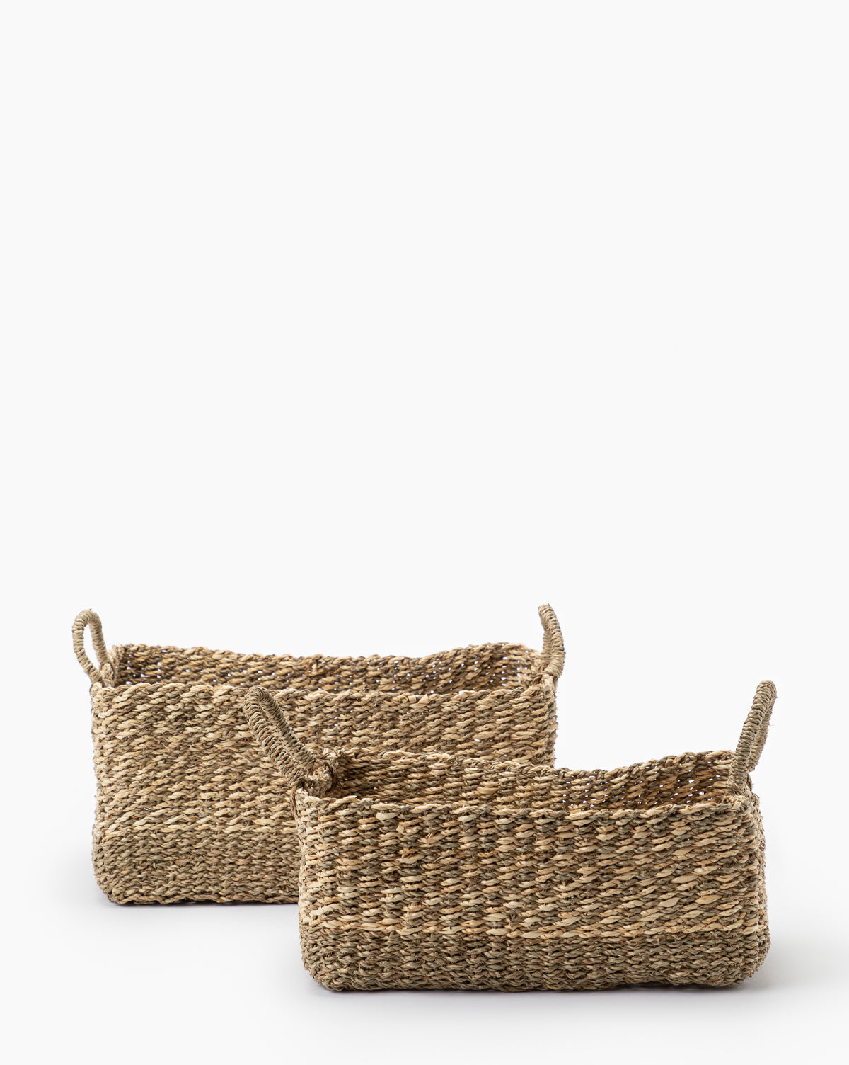 Two Cordova Baskets, featuring two handles and crafted from natural fibers, are placed side by side on a white background. One woven grass basket is positioned slightly in front of the other.