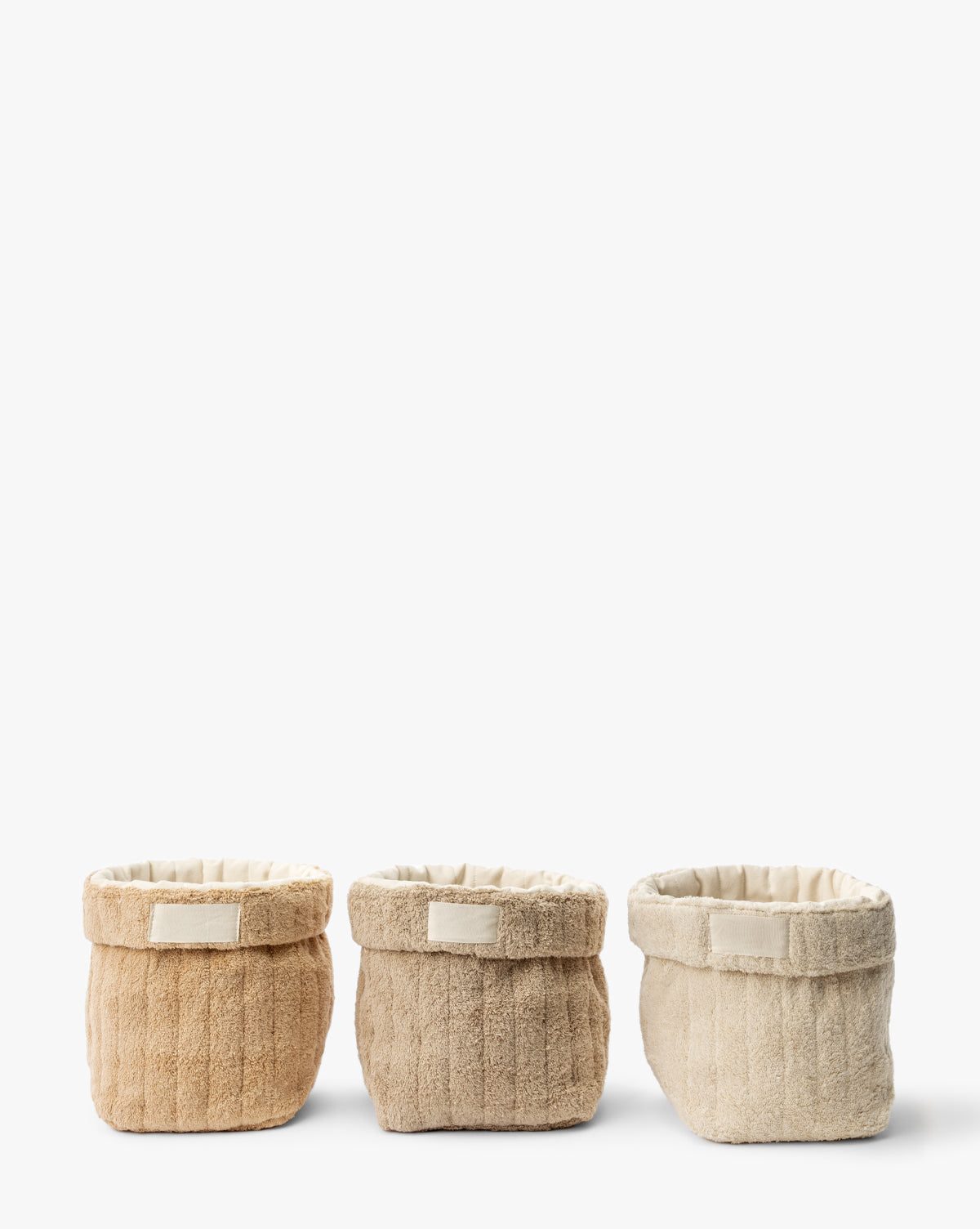 The Cotton Terry Cloth Baskets (Set of 3) in beige, light brown, and cream are neatly arranged side by side against a white background, providing a stylish way to organize your space, by McGee & Co.