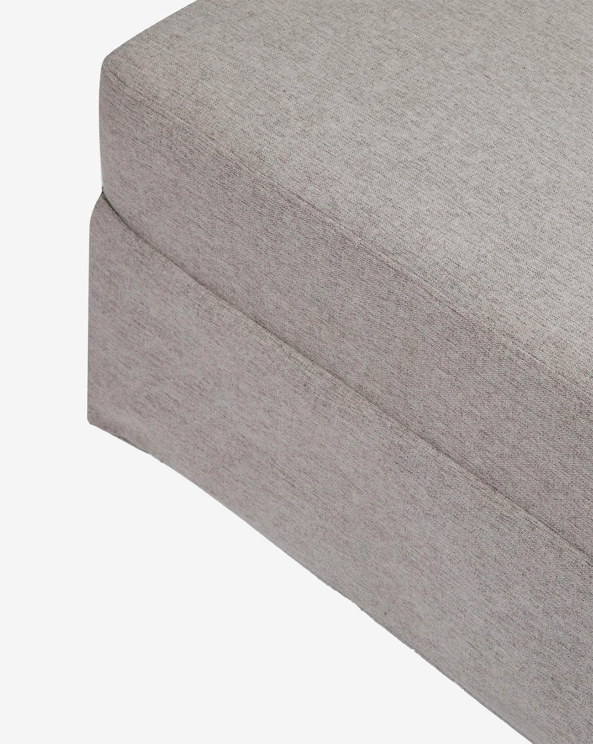 Close-up of the corner of a light gray Million Dollar Baby Crawford Gliding Ottoman cushion with a tailored skirt in eco-performance fabric, shown against a white background. McGee & Co.
