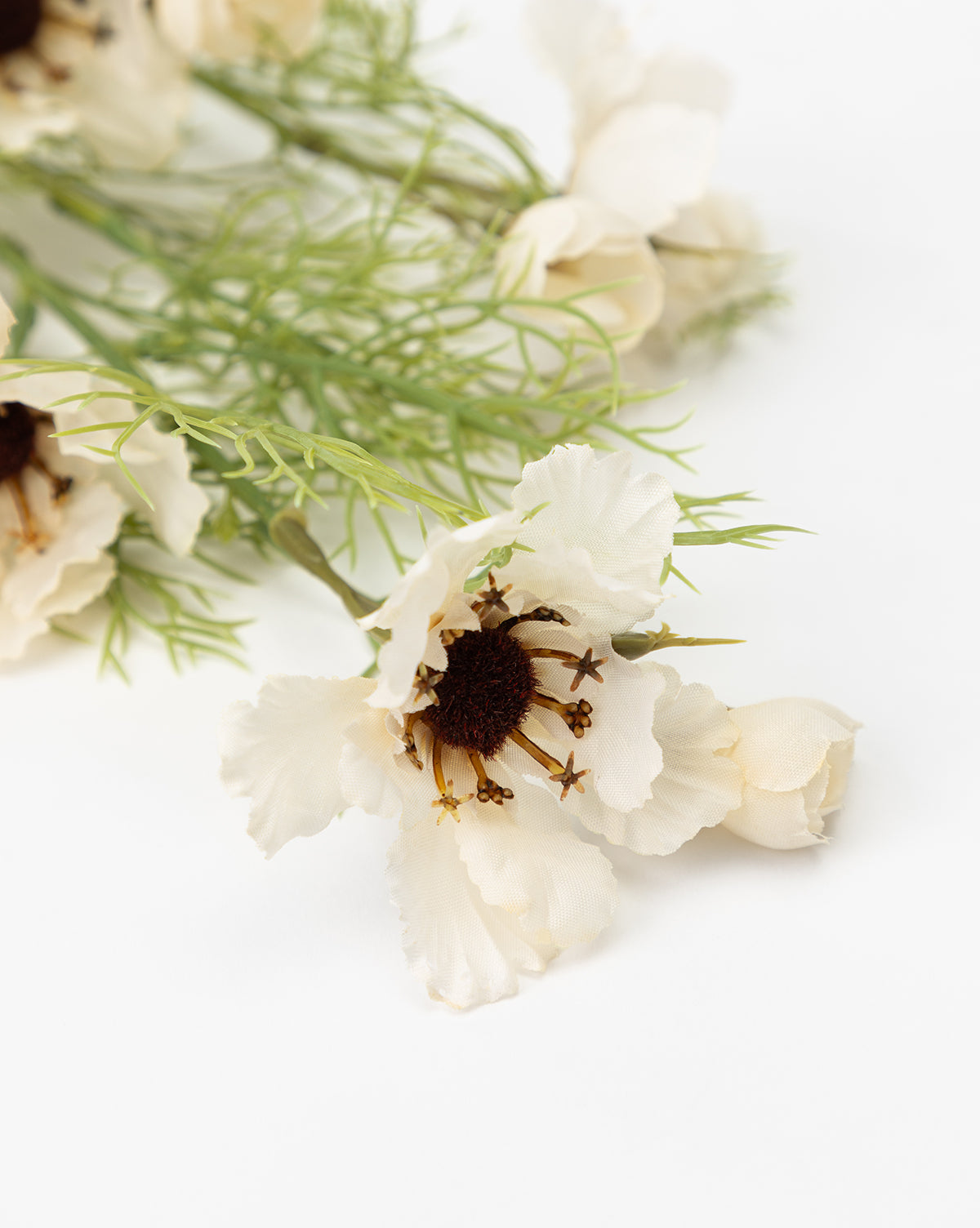 A close-up of the Cream Cosmos Stem showcases white artificial flowers with dark brown centers and green leaves, artfully arranged as a faux floral display against a white background, by McGee & Co.