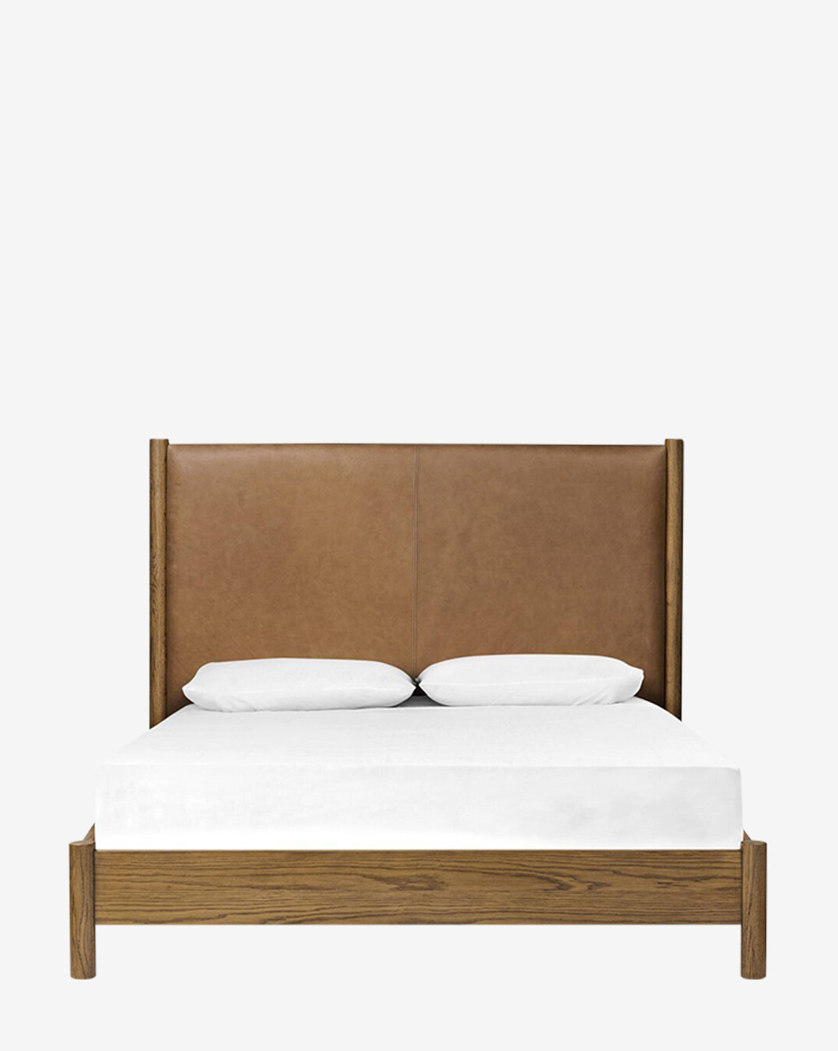 The Four Hands Crue Bed features a tall brown leather upholstered headboard, an oak frame, white bedding, and two white pillows, displayed against a plain white background. McGee & Co.