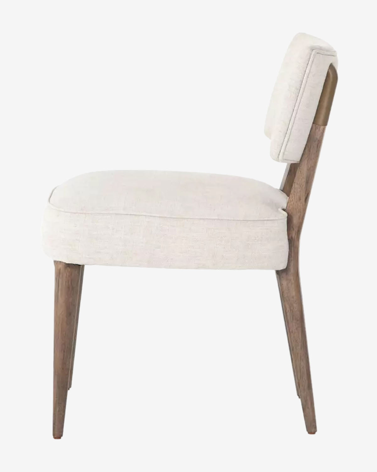 Side view of the Cyrene Dining Chair, showcasing its cushioned ivory performance fabric seat and backrest with four angled wood legs, all set against a plain white background by McGee & Co.