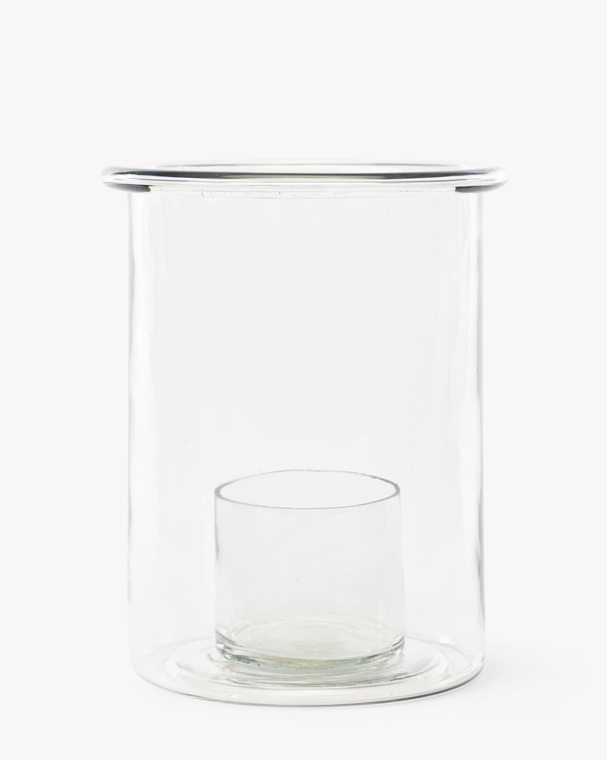 The Cyrus Hurricane is a clear glass candle holder with a cylindrical outer vessel and an inner glass holder at the base, perfect for adding modern elegance to your home decor, by McGee & Co.