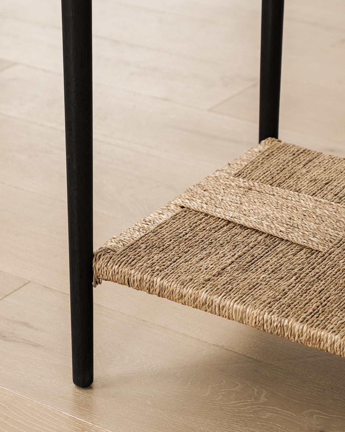 Close-up of the Dana 2-Drawer Console featuring oak finish, black legs, and a woven natural fiber shelf on light wood flooring—ideal for entryway decor, by McGee & Co.