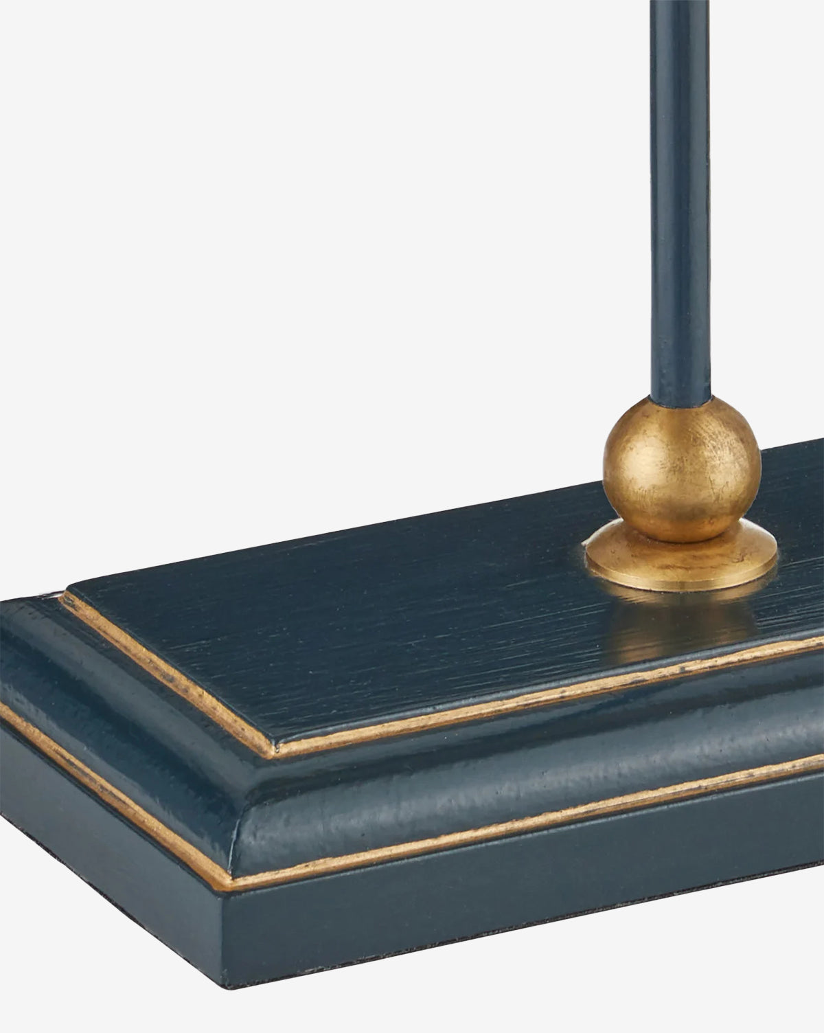 A close-up of the Daphne Navy Table Lamp, showcasing its dark blue rectangular base with gold accents and a gold sphere where the stem connects to the base, by McGee & Co.