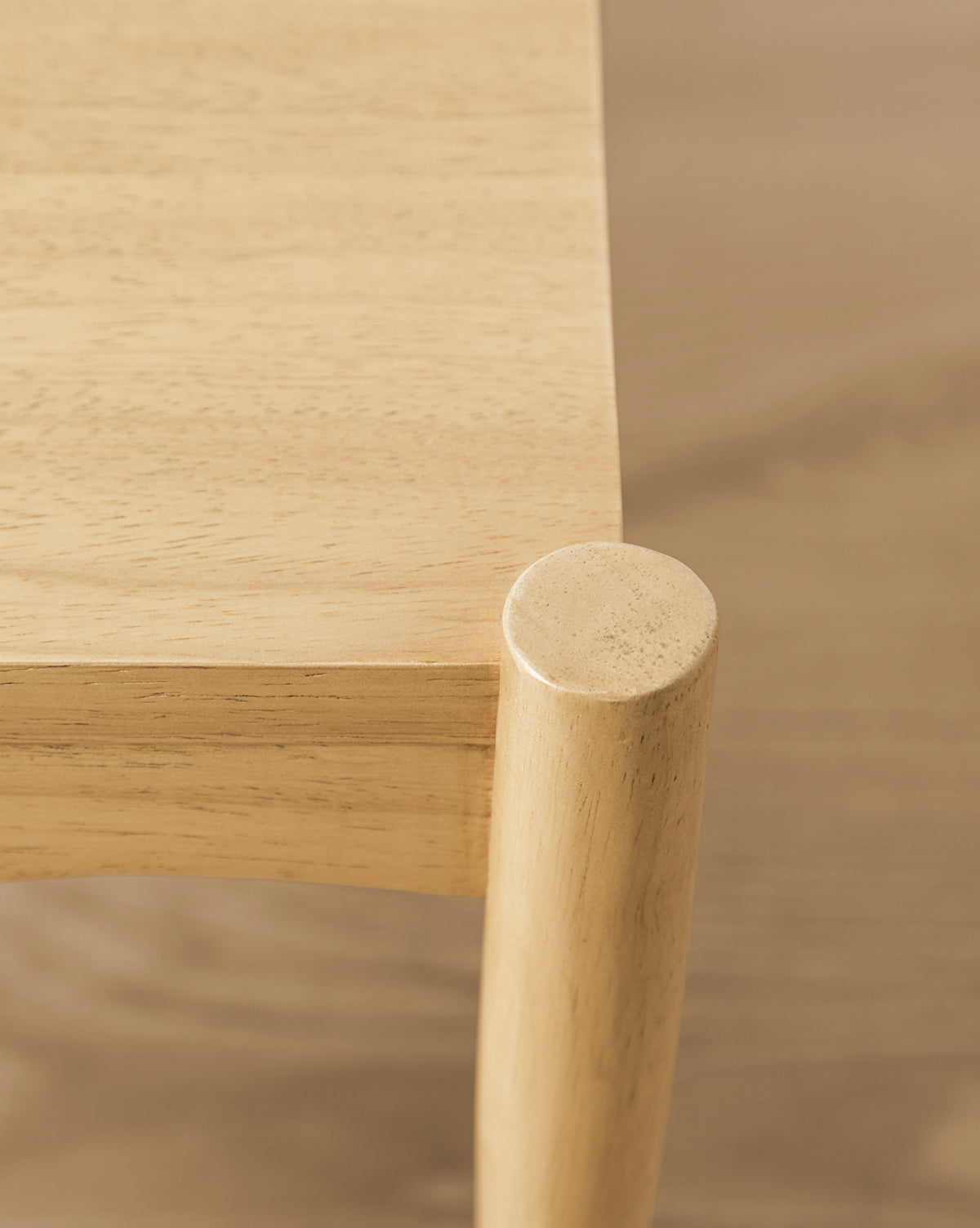 Close-up of a light wooden table’s smooth surface and rounded edge with one cylindrical leg—perfect to pair with the Darcy Kids Chairs (Set of 2) for a stylish childrens space, by McGee & Co.
