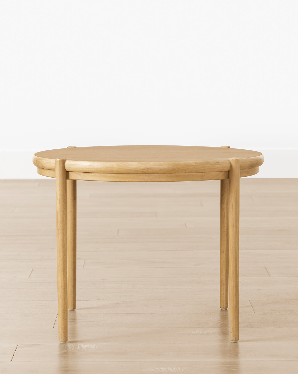 The Darcy Kids Table is a round, white oak kids table with four straight legs—ideal as a modern coffee or crafts table—shown on a light wood floor against a plain white wall, by McGee & Co.