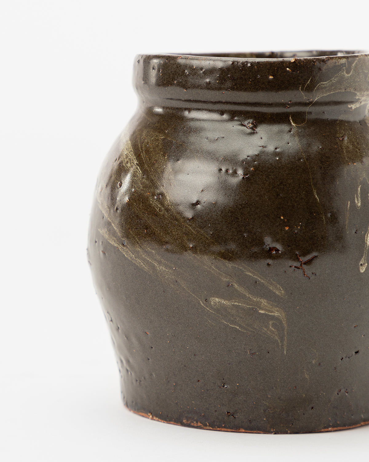 A close-up of the Dark Glazed Ceramic Vase shows its irregular shape, textured surface, and subtle lighter streaks. This classic vase features a rich, glossy finish and stands out against a plain white background.