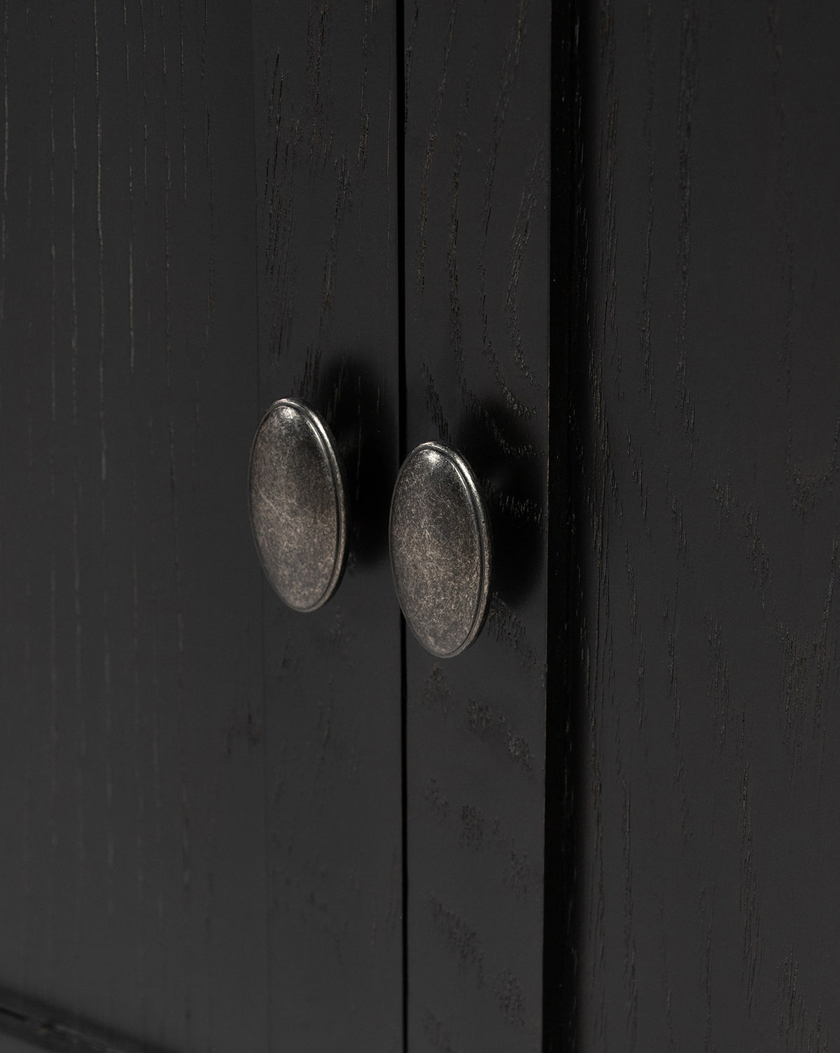 Close-up of two aged brass hardware knobs on dark wood cabinet doors with textured grain, featured on the Dixon Sideboard, by McGee & Co.