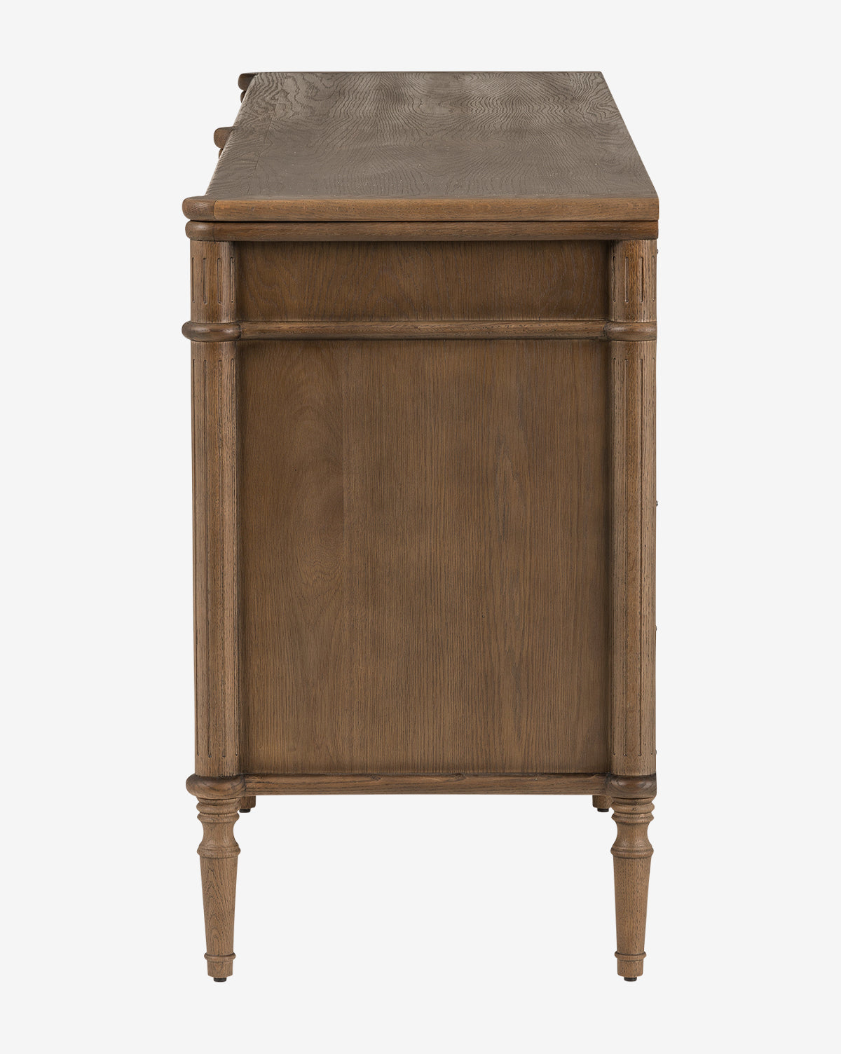 Side view of the Dixon Sideboard, featuring smooth oak, vertical molding, aged brass hardware, and four tapered legs, shown against a plain white background by McGee & Co.