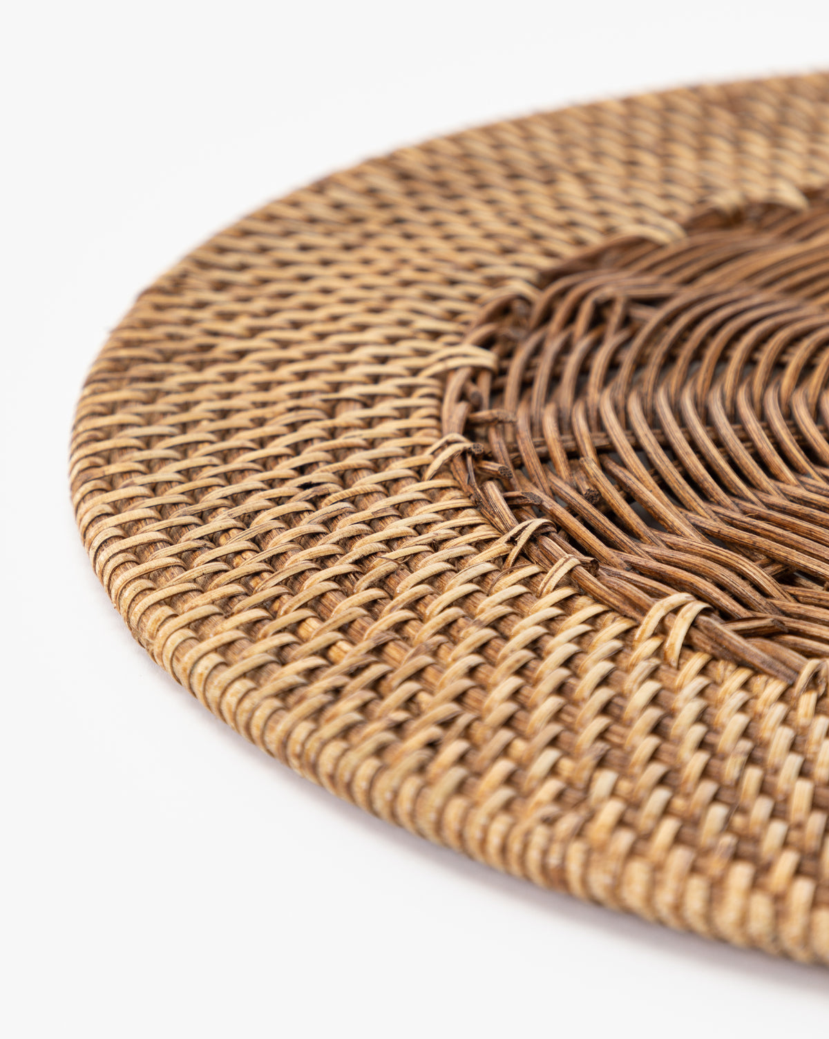 Close-up of the Davin Placemat, a round wicker mat with a braided pattern and contrasting brown center and lighter edge on a white background—ideal for adding a coastal touch to your table setting, by McGee & Co.