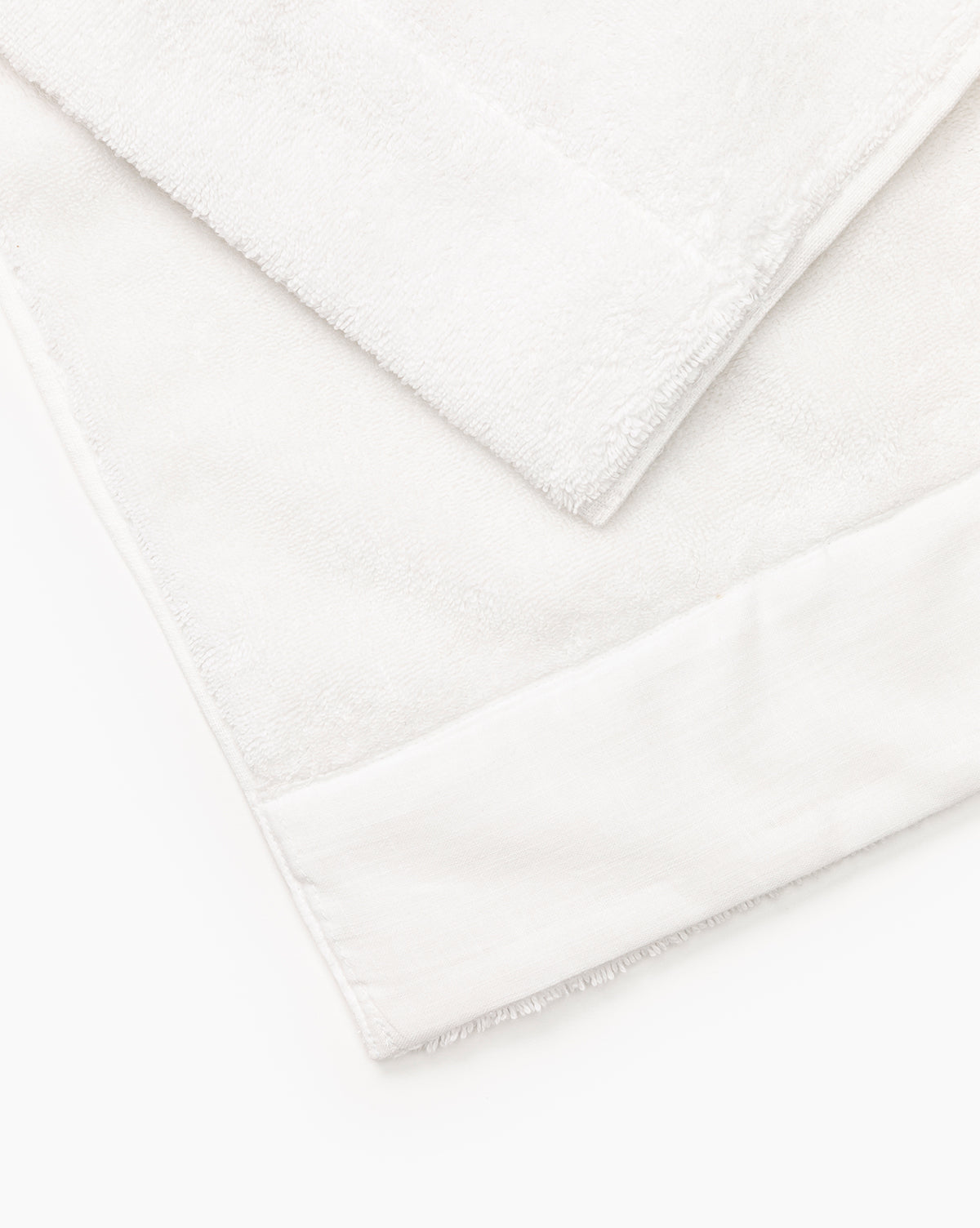 Two plush white cotton towels from the Dedra Bath Collection are neatly layered, featuring a soft texture and subtle border detail, set against a white background.