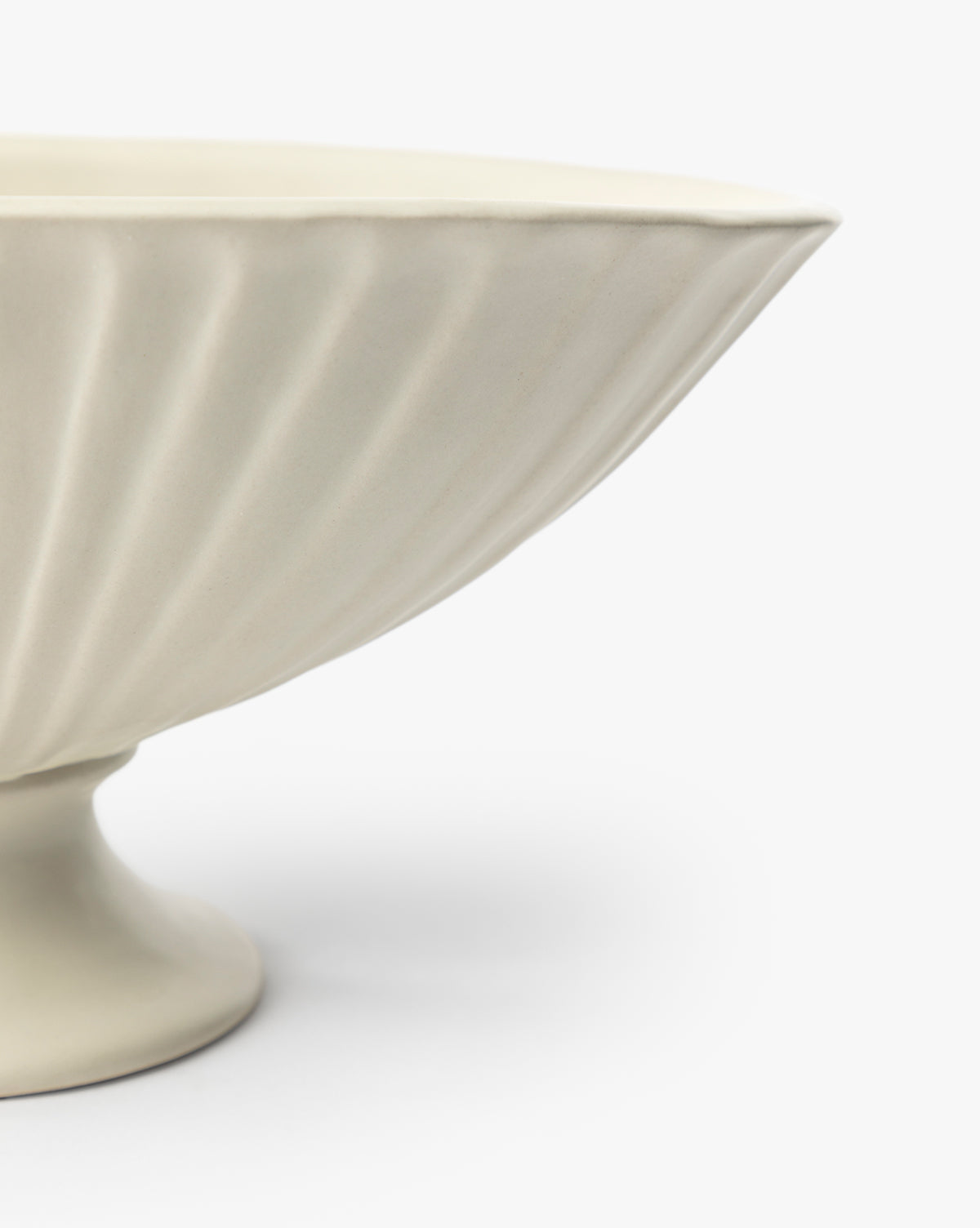 A close-up of the Delphi Footed Bowl, featuring cream-colored stoneware with a fluted textured design and satin glaze, shown against a plain white background, by McGee & Co.