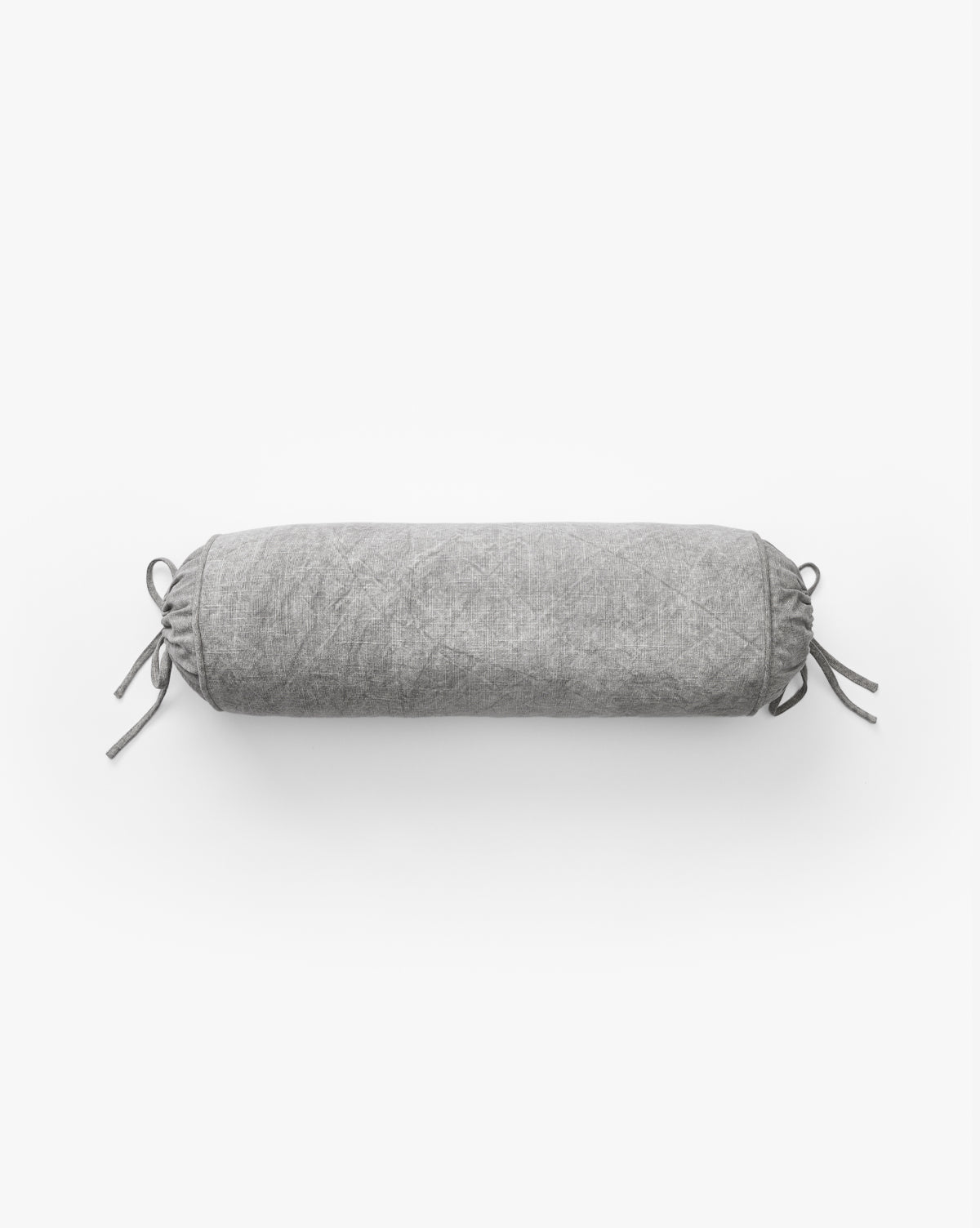 The Delphine Bolster Pillow features a cylindrical, vintage-inspired design in light gray stonewashed cotton with drawstring closures and tied bows at both ends, shown on a plain white background.