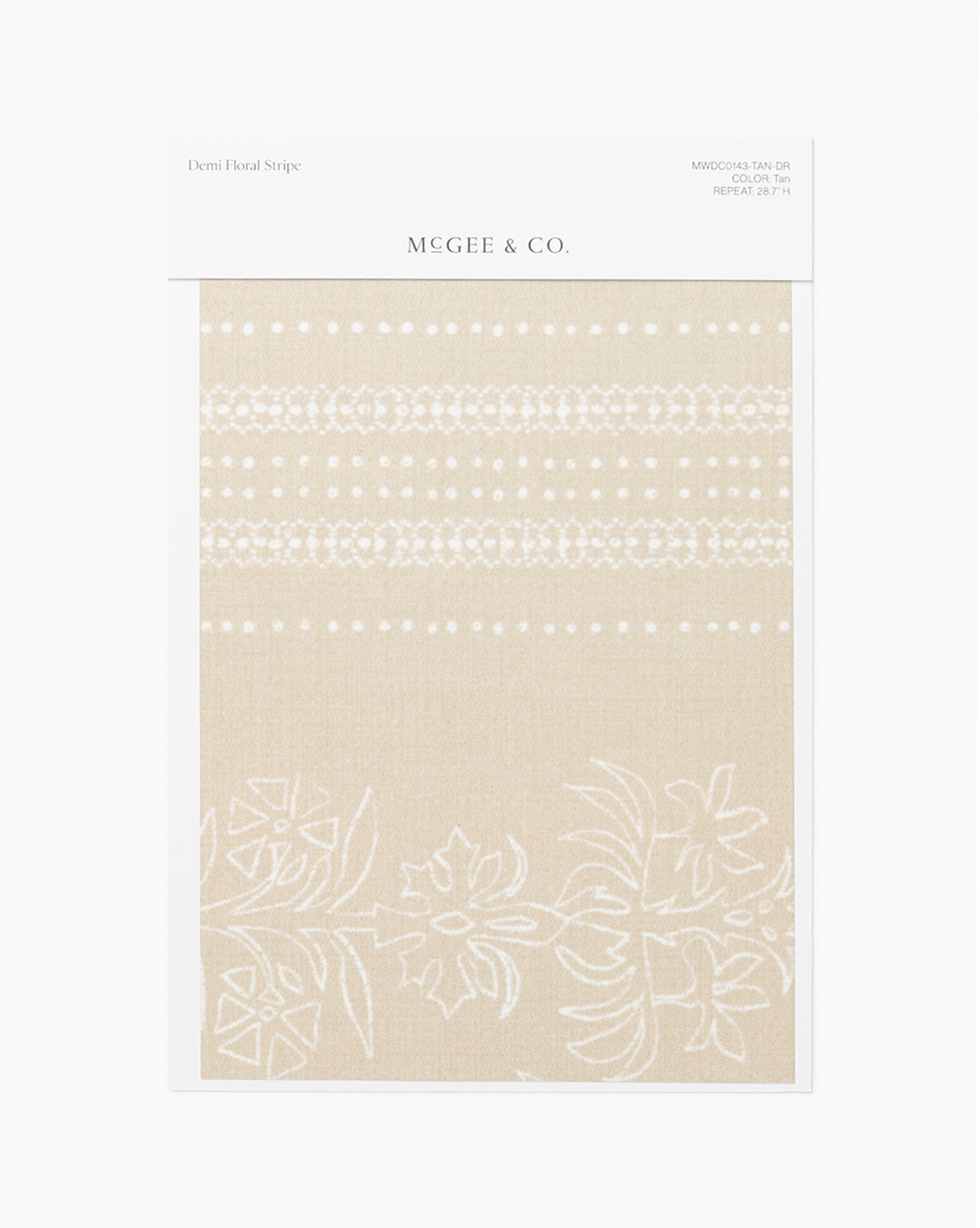 A Demi Floral Stripe Wallpaper Swatch by McGee & Co. shows a tan background with white floral and dotted stripes, reminiscent of elegant wallpaper. The fabric sample is attached to a white card featuring product details at the top, and is branded with McGee & Co.