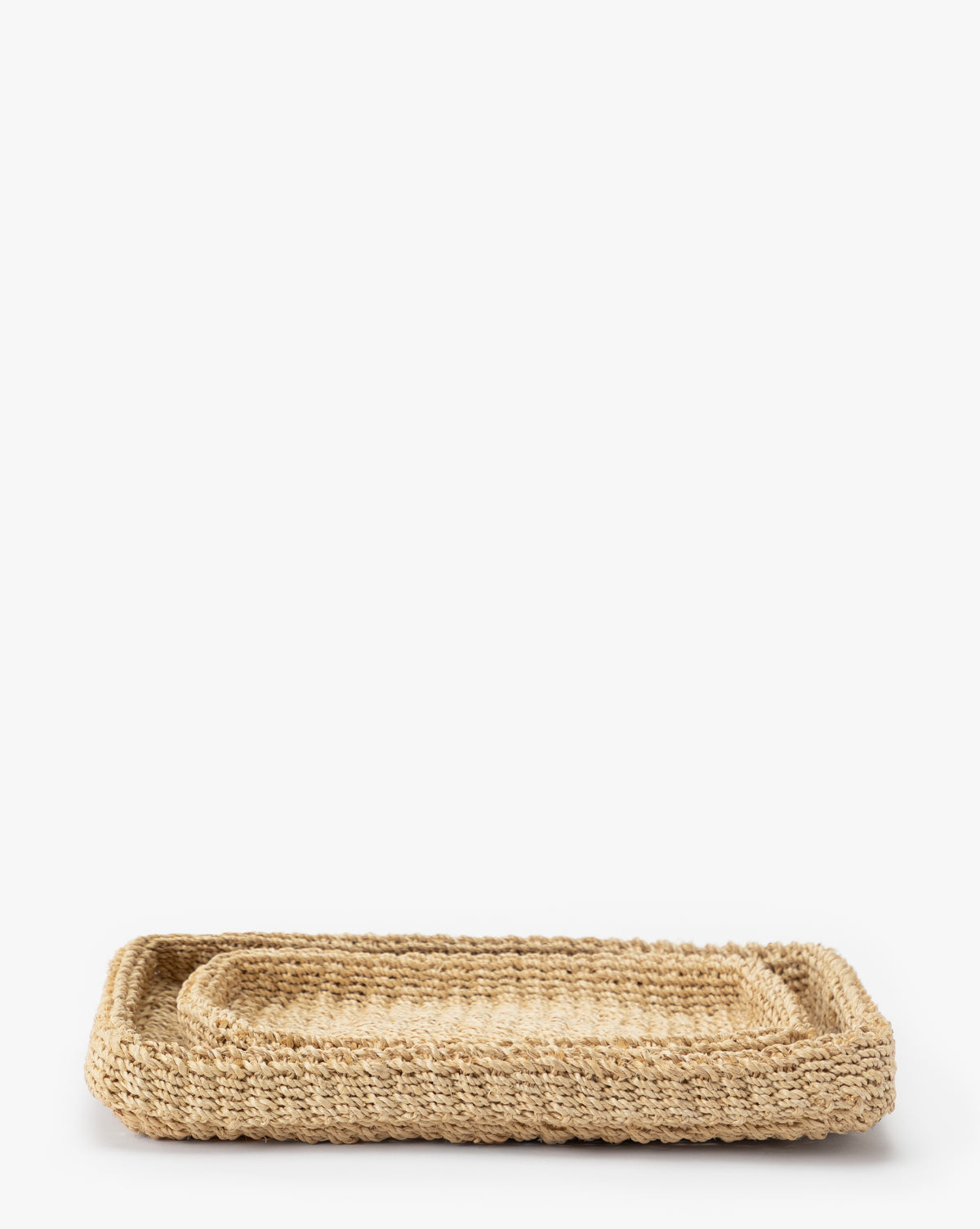 The Deryn Woven Tray, a rectangular abaca fiber tray with raised edges and textured design, is shown on a white background. Stacked with a smaller matching tray inside, it brings natural charm to any space.