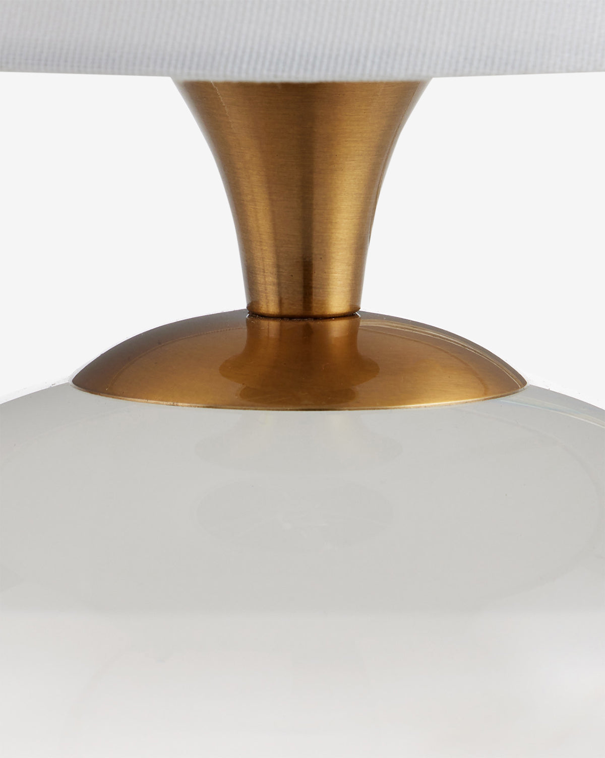 Close-up of the Diantha Table Lamp with an antique brass stem and base, a glossy white rounded body, and part of its white lampshade at the top, by McGee & Co.