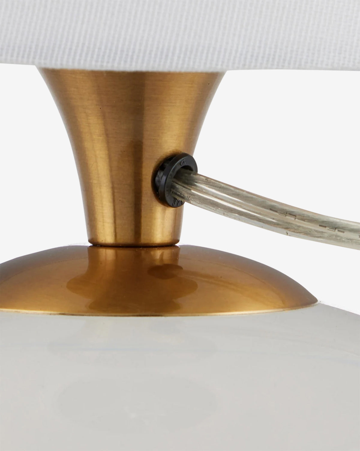 Close-up of the Diantha Table Lamp, showcasing its antique brass stem, gold-toned metal details, optic crystal base, clear power cord at the socket, and a glimpse of the white lampshade above by McGee & Co.