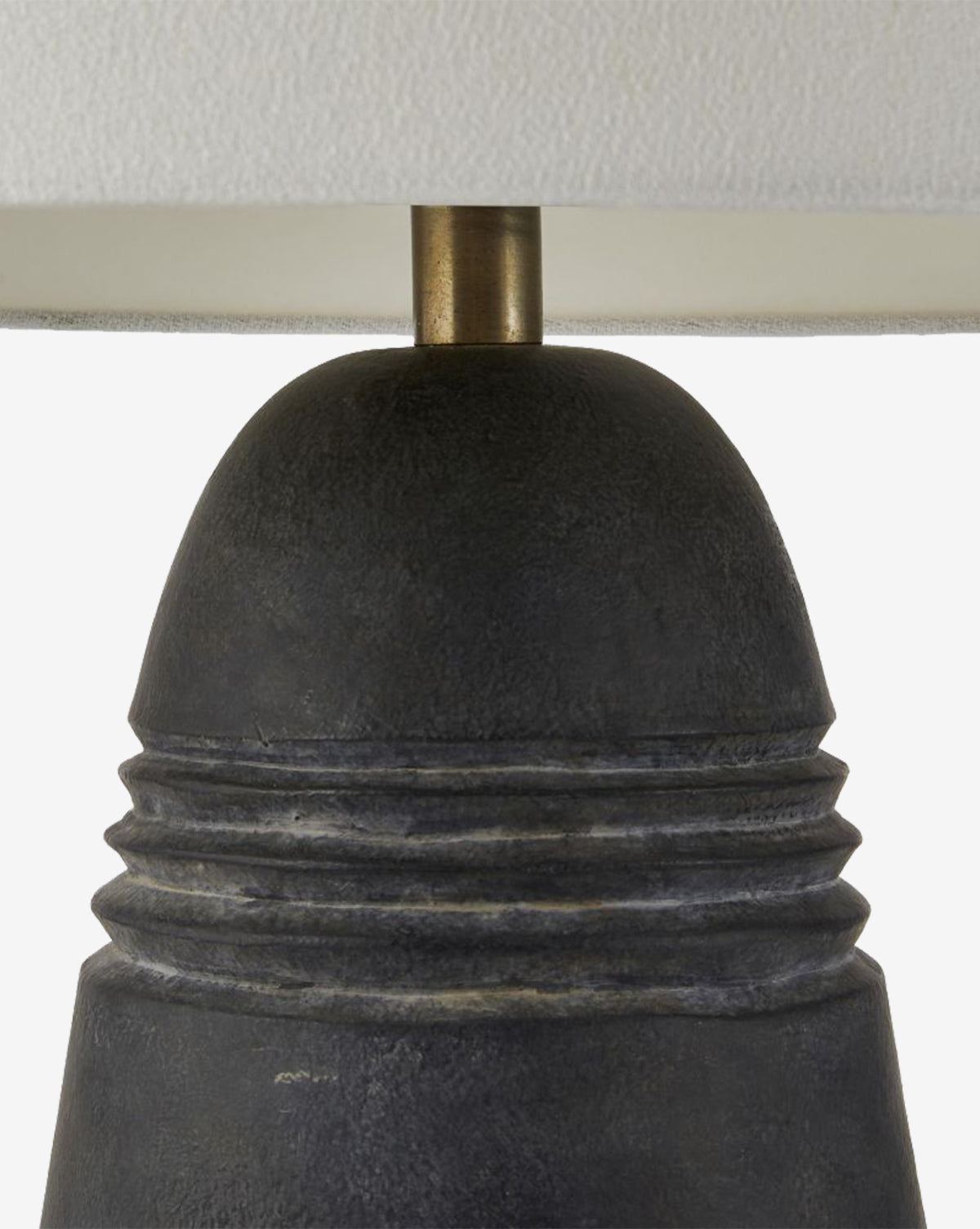 Close-up of the Django Table Lamp, showcasing its textured dark terracotta base with horizontal ridges, brass-toned rod, and a white linen shade, by McGee & Co.