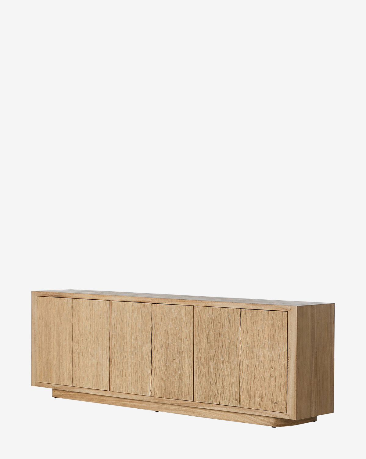 The Drayton Sideboard features four vertical, textured doors and a light natural wood finish with clean lines. This minimalist piece sits on a low, flat base, ideal for entryways and shown against a plain white background by McGee & Co.