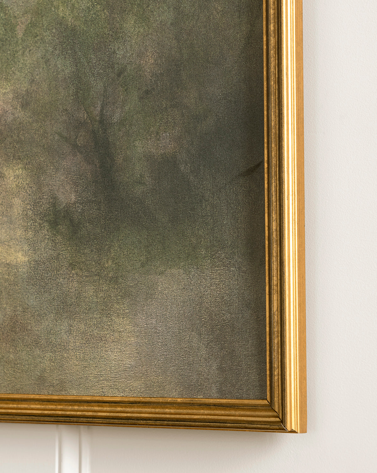 Close-up of the bottom right corner of Dream State, a framed painting with a gold frame. The expressive artwork features textured, muted green and brown tones evoking a dramatic landscape. Part of a white wall appears in the background, by McGee & Co.