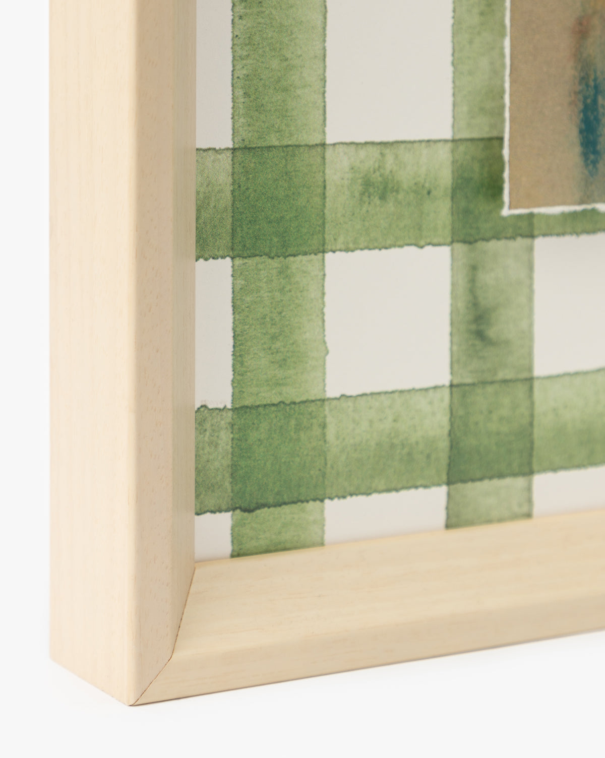Close-up of a light wooden picture frame corner showcasing Dreamscape artwork—a green, watercolor-style plaid on watercolor paper—adding a fresh touch to your home decor, by McGee & Co.