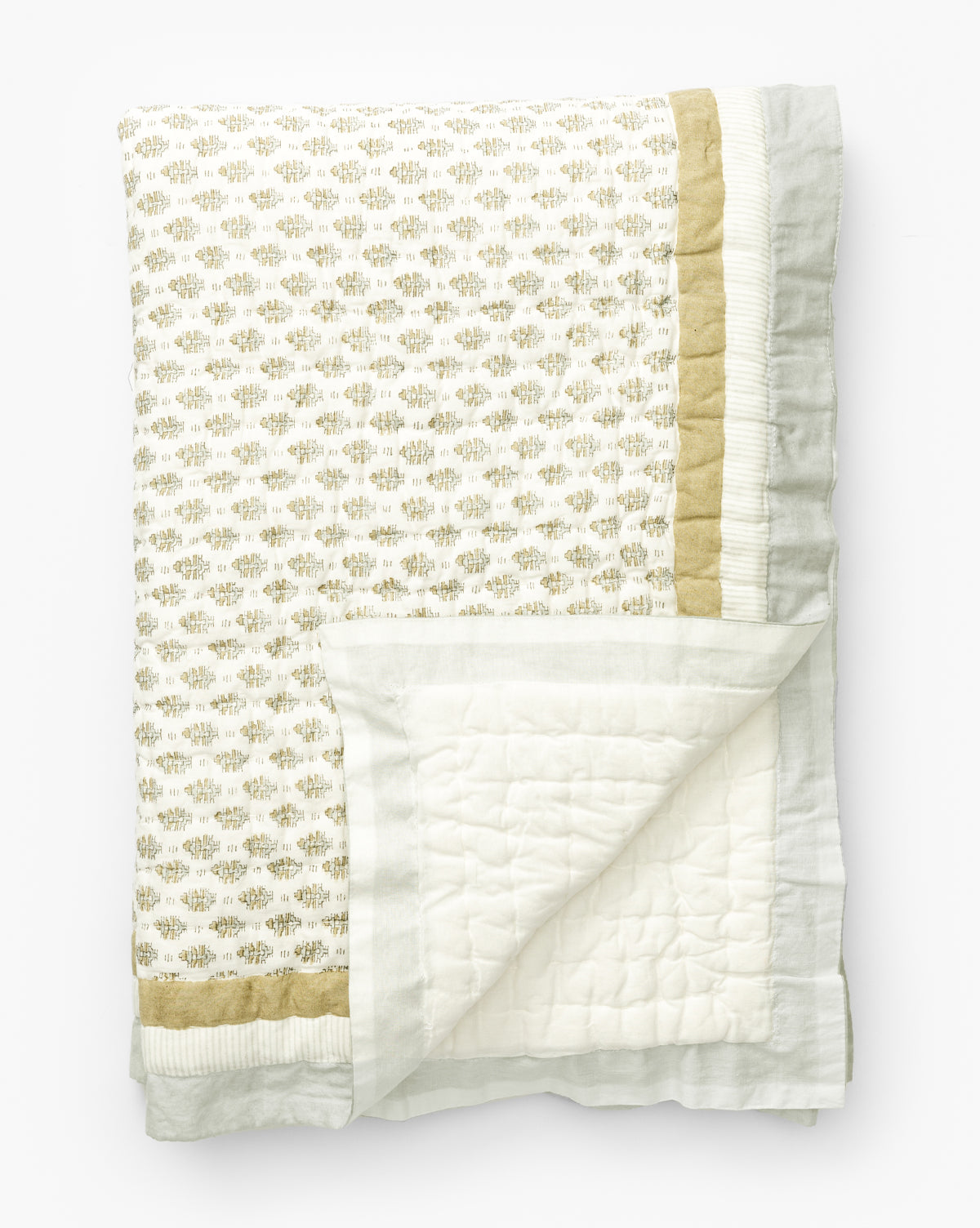 The Dulcie Block Print Kids Quilt by Renuka Inc. is a folded cotton quilt featuring a gold and light gray block print pattern with matching borders; the reverse side is plain white with stitched squares. McGee & Co.