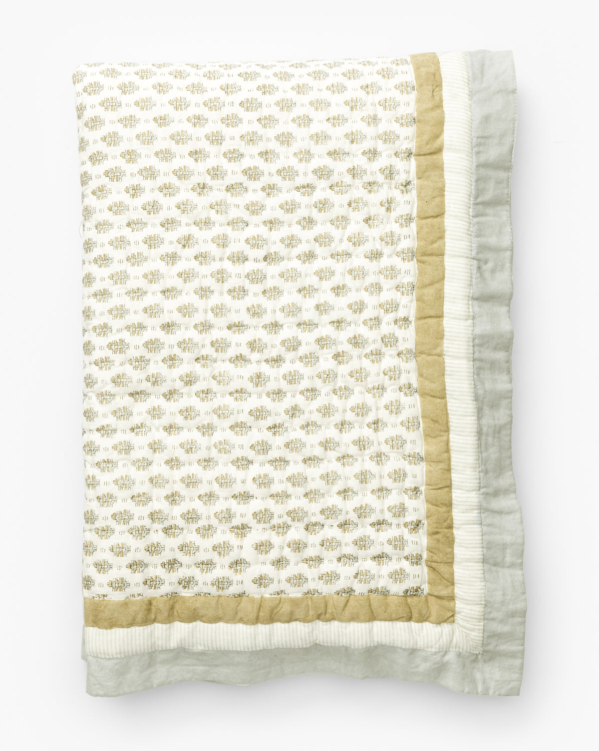 The Dulcie Block Print Kids Quilt by Renuka Inc. is folded to show its white center with small, light gold block print motifs, a solid gold border, and an outer white ruffled edge, all displayed on a white background. McGee & Co.